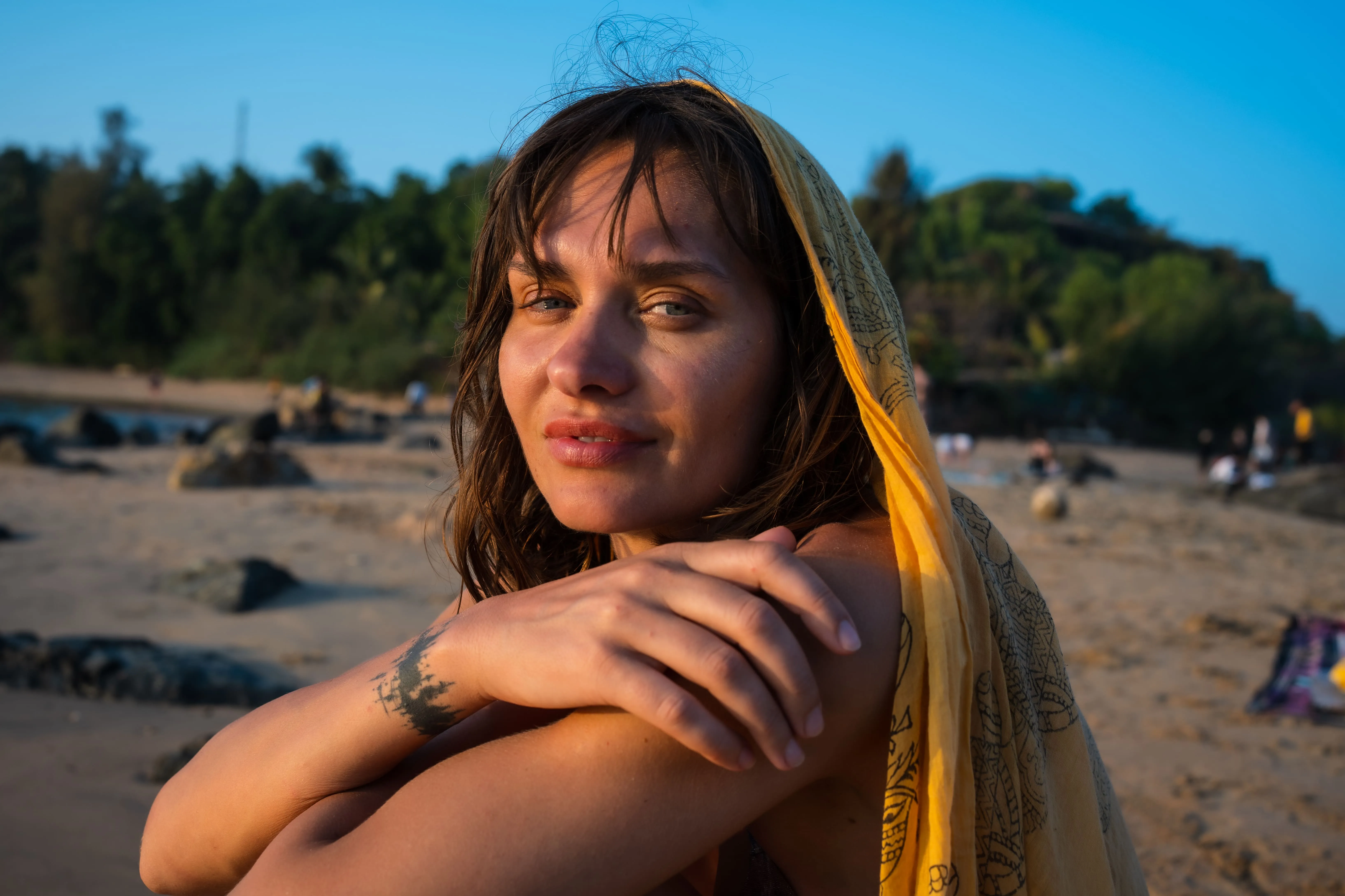 Close-up beach portrait of a woman under a yellow patterned scarf in Goa.