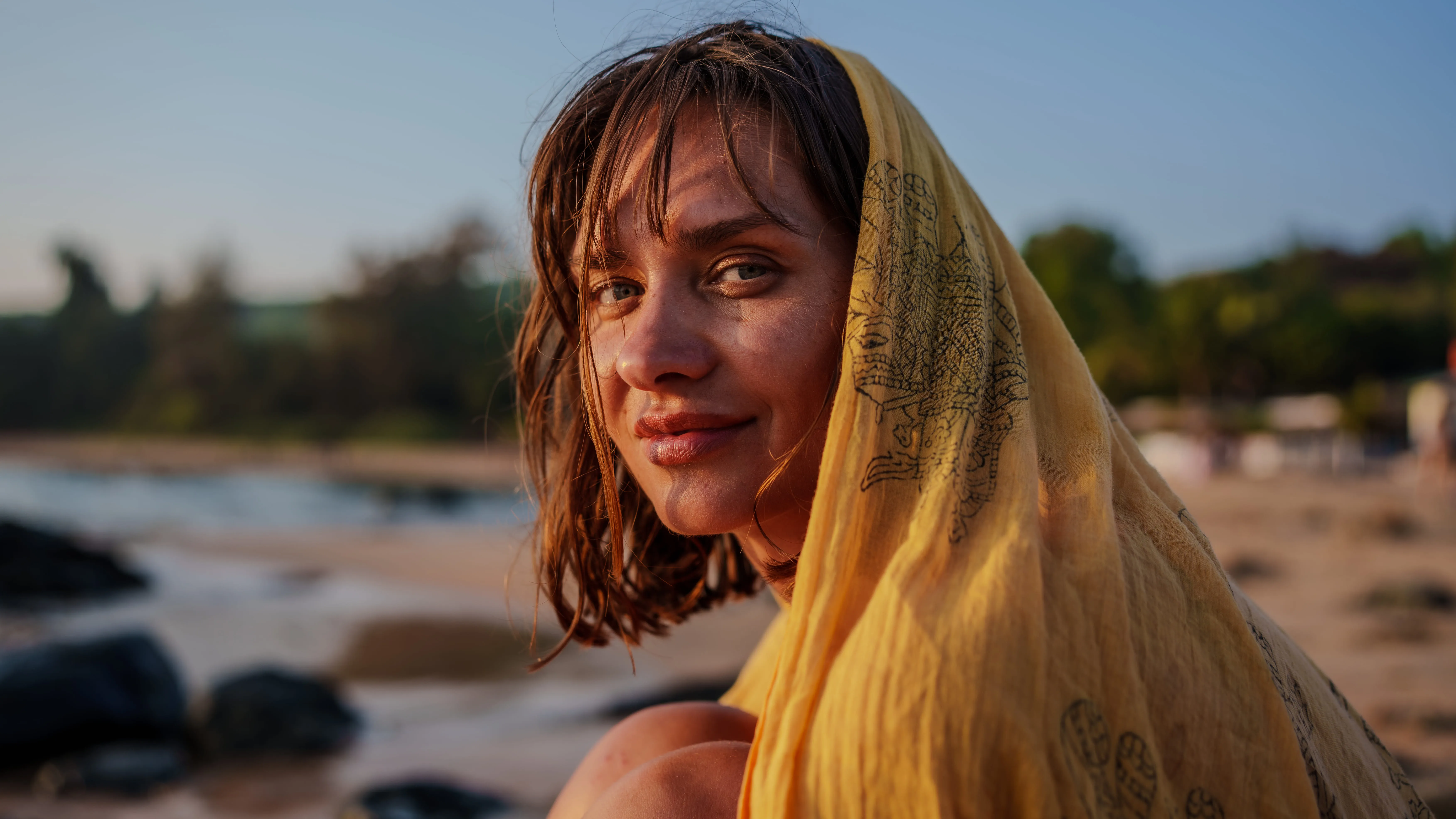 Tight portrait of a woman in a yellow patterned scarf on a Goa beach.