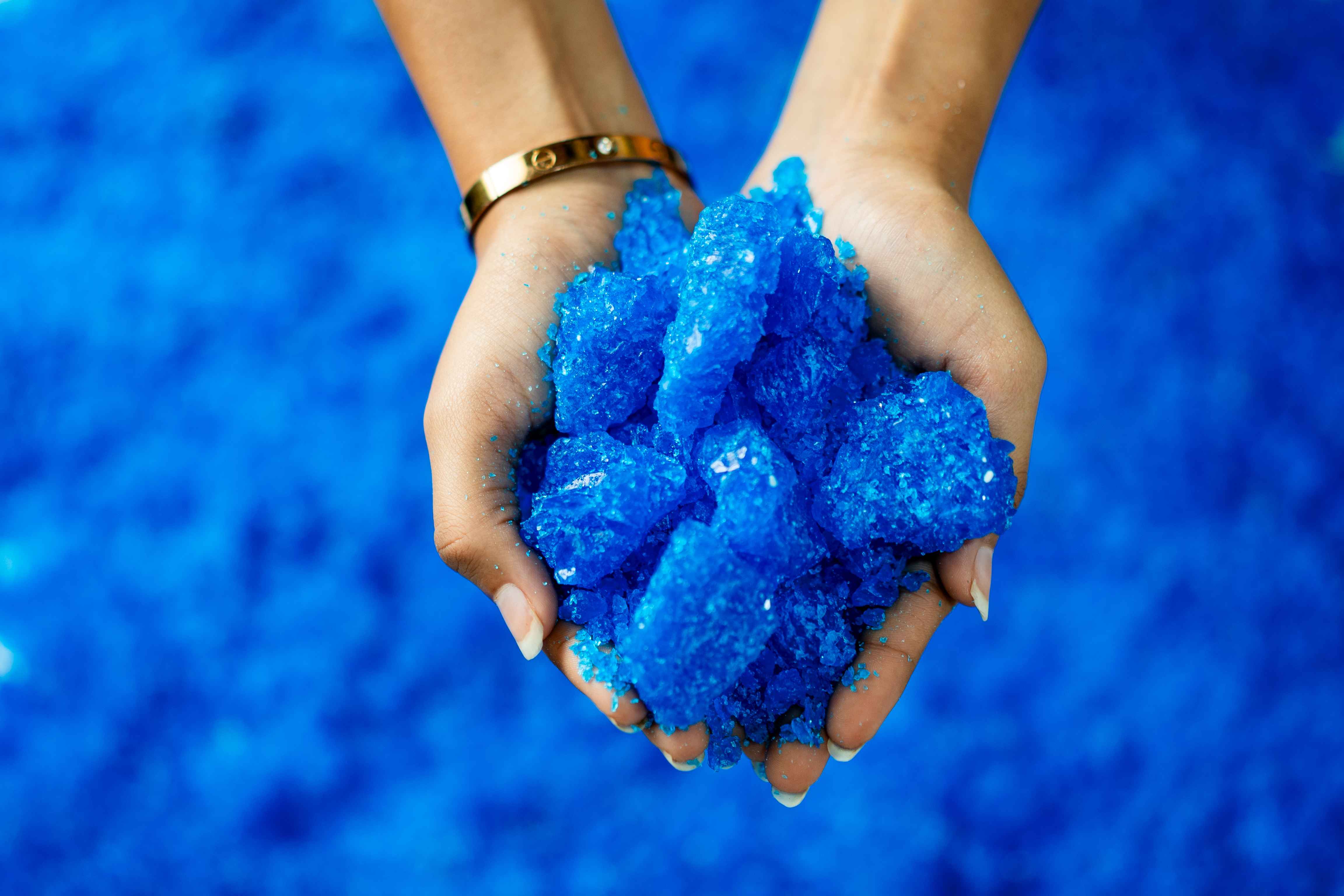 Hands holding copper sulphate crystals for Eva Chemlinks.