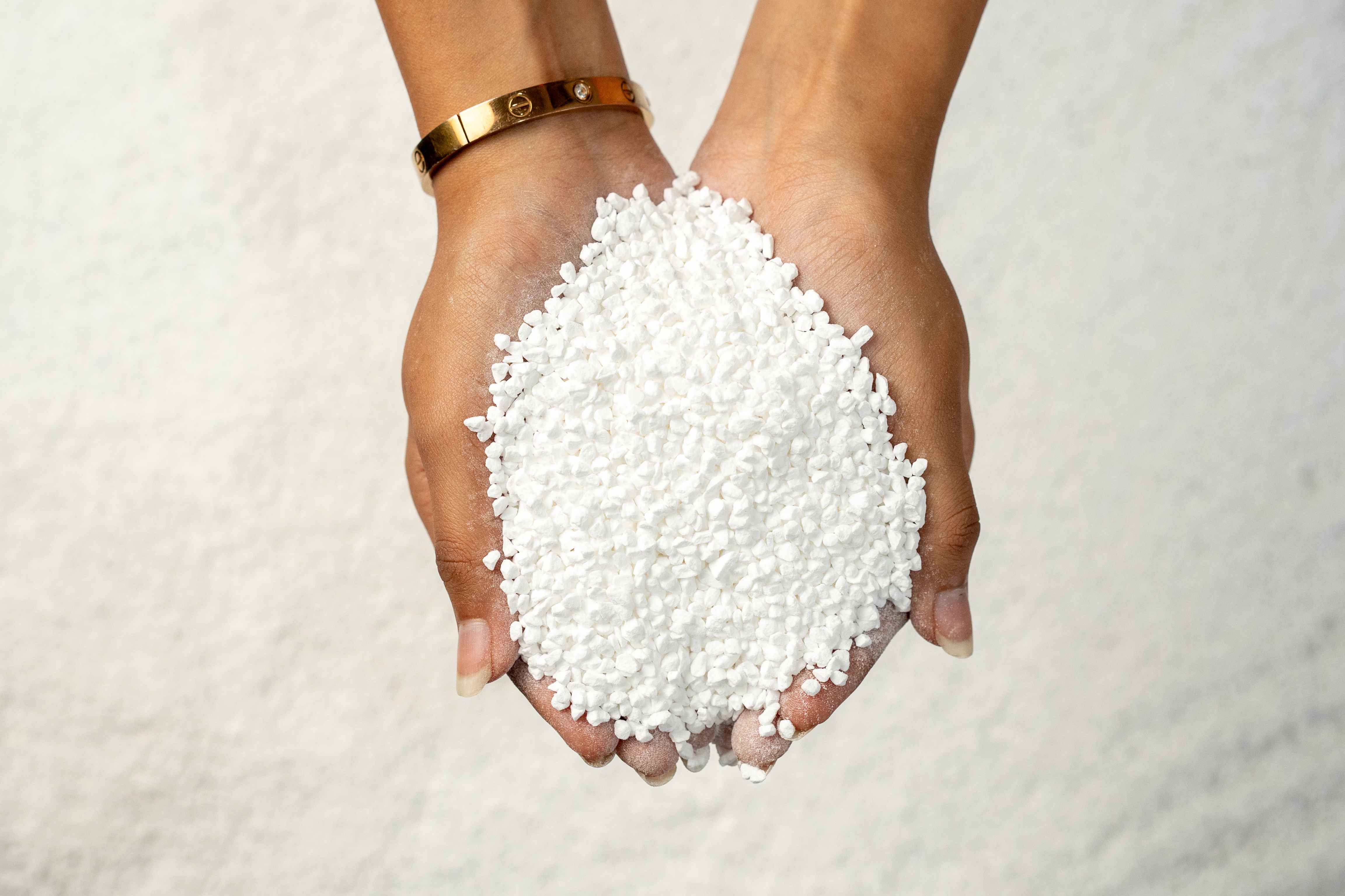 Hands holding white TCCA 90% granules for Eva Chemlinks.