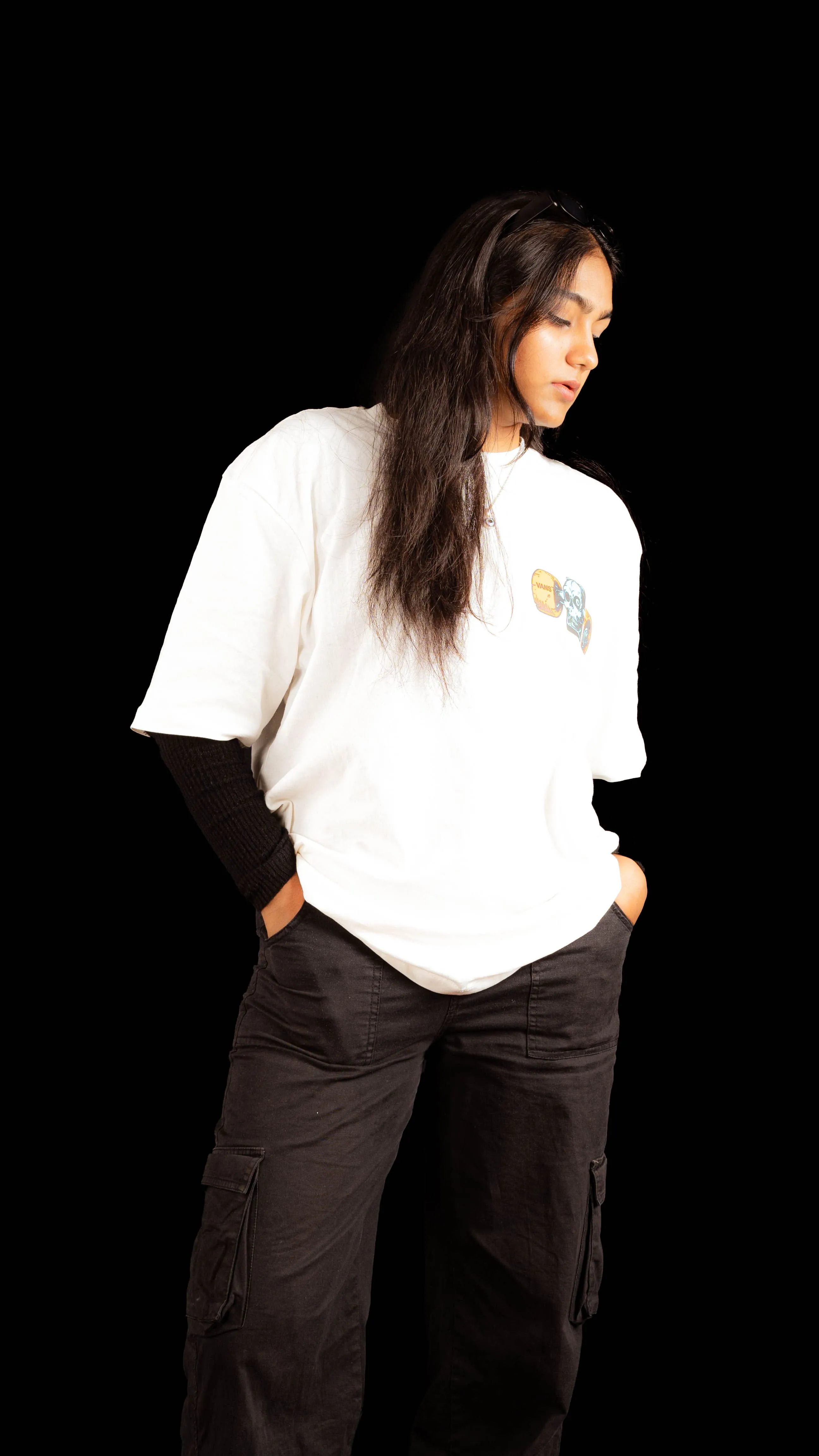 Woman in a white graphic T-shirt and black cargo trousers in a studio portrait.