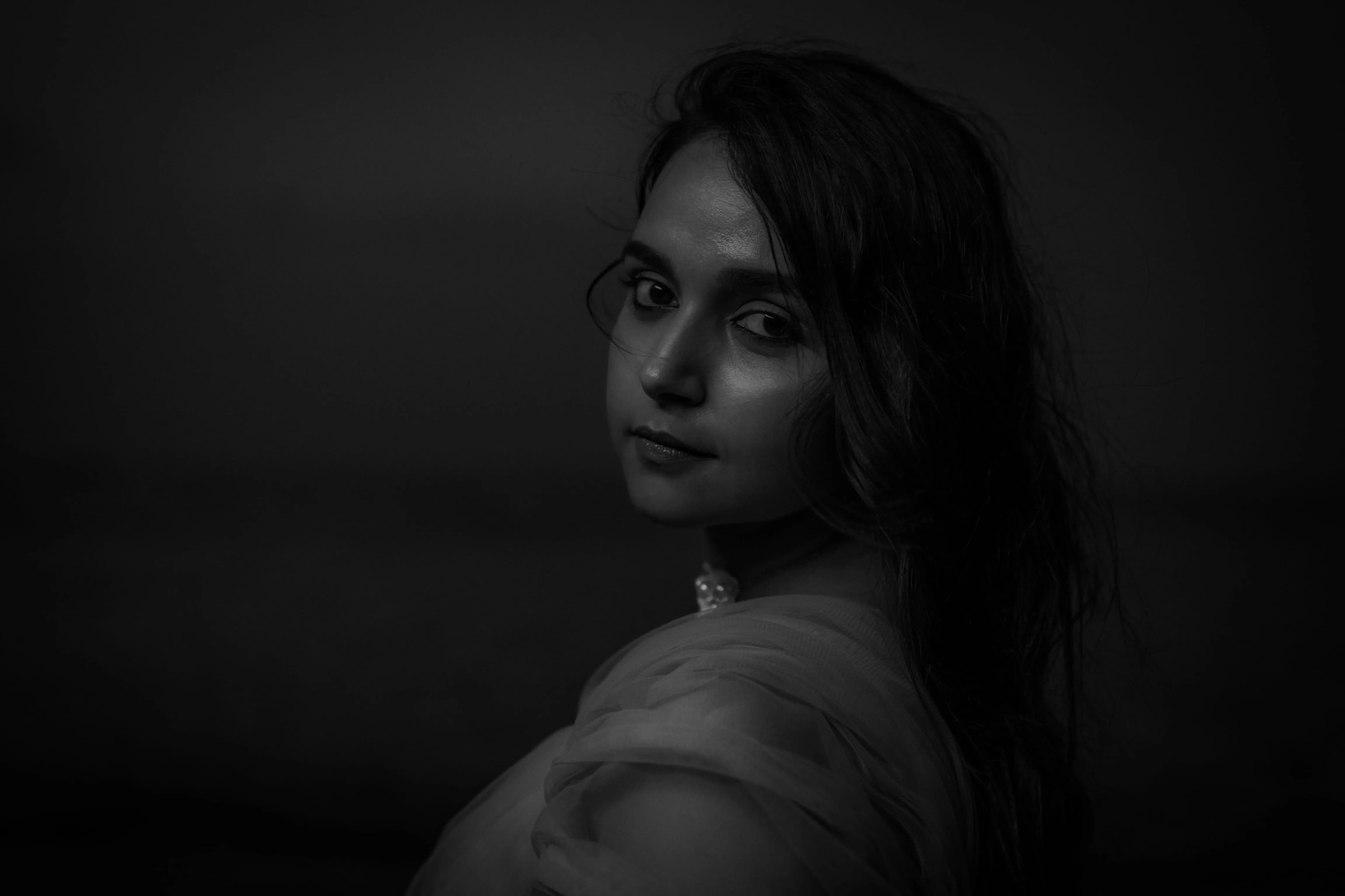 Black-and-white portrait of a woman partially wrapped in pale fabric.