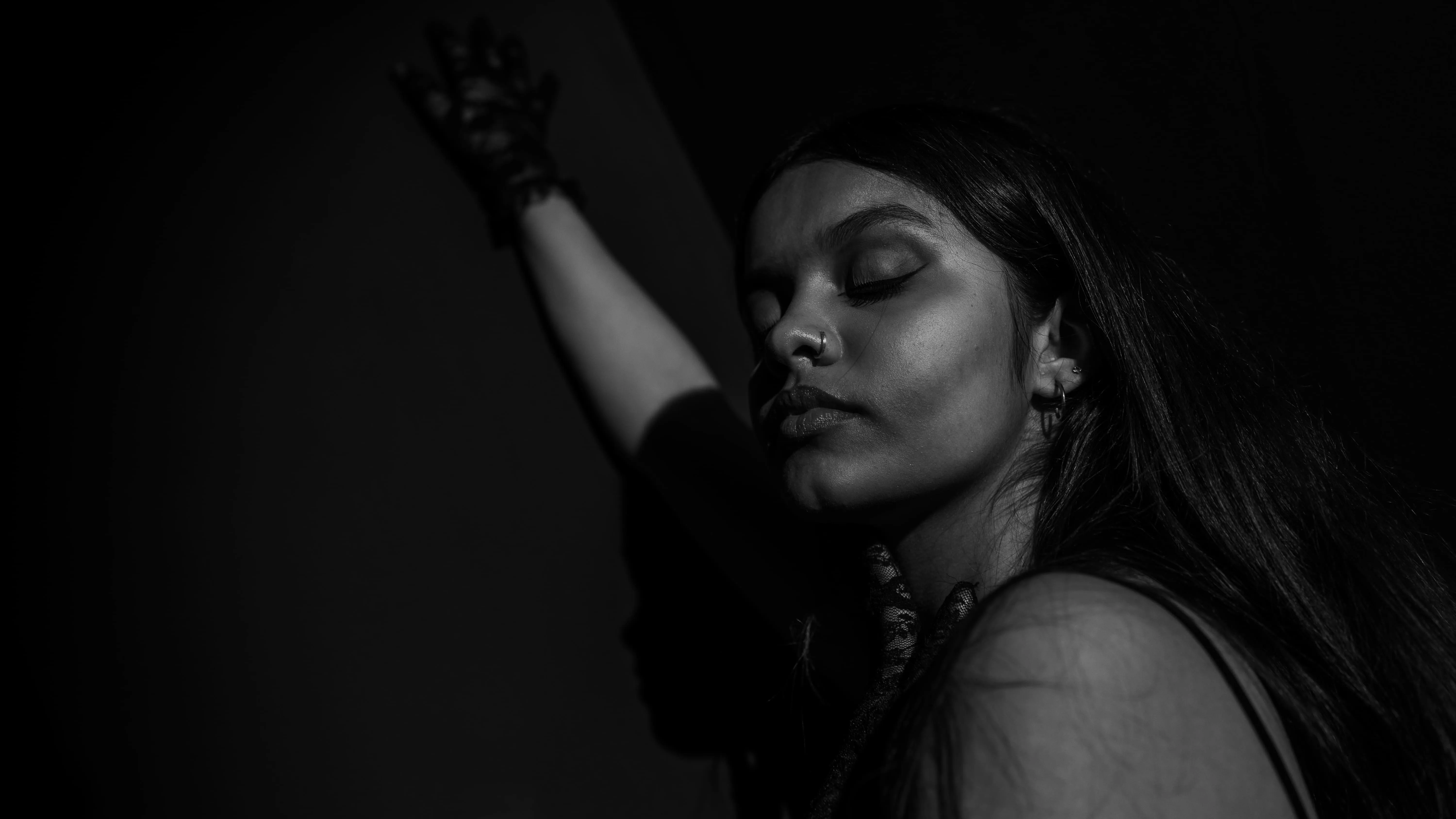 Black-and-white portrait of a woman with her eyes closed against a dark background.