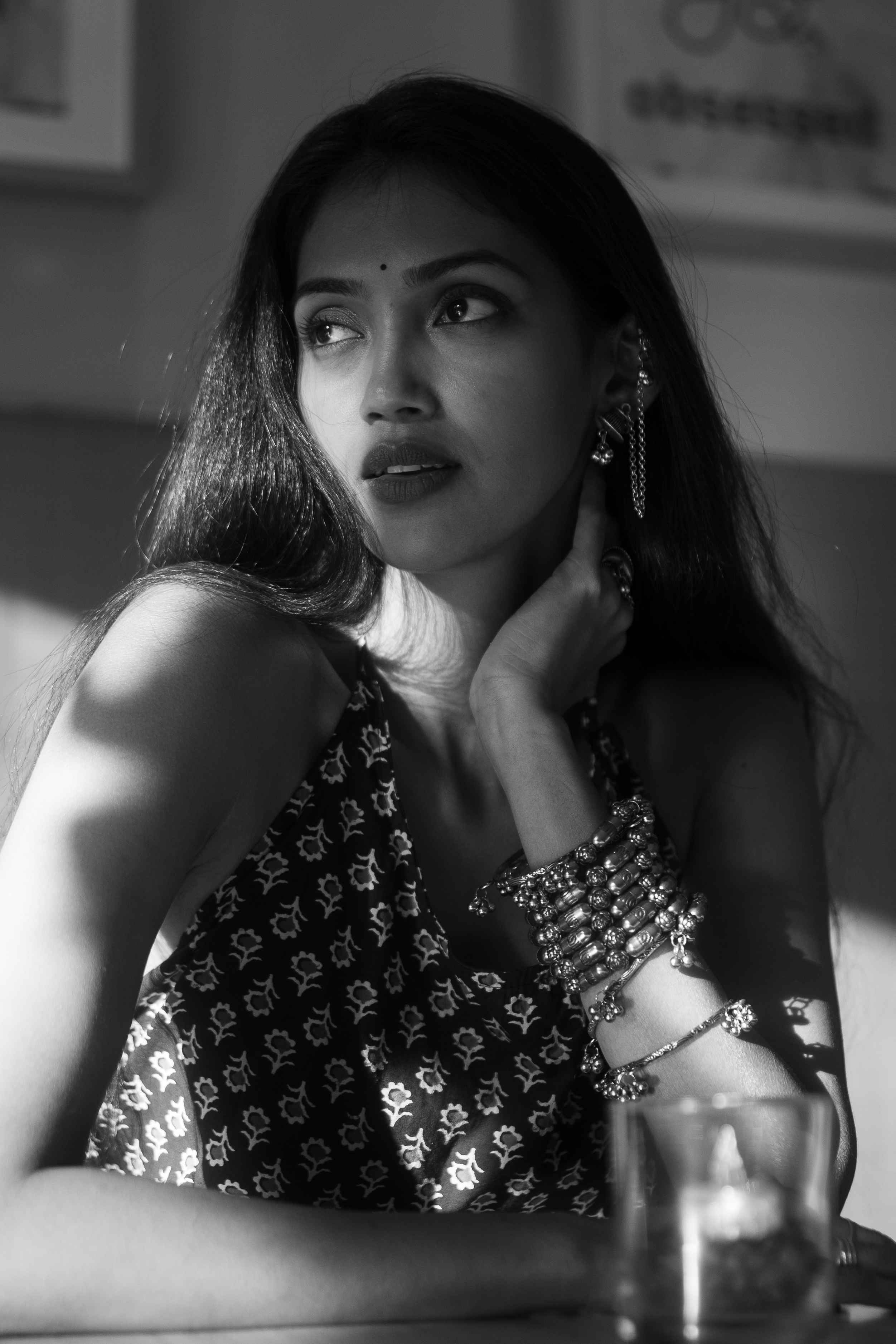 Black-and-white portrait of a woman in a patterned top wearing layered jewellery.