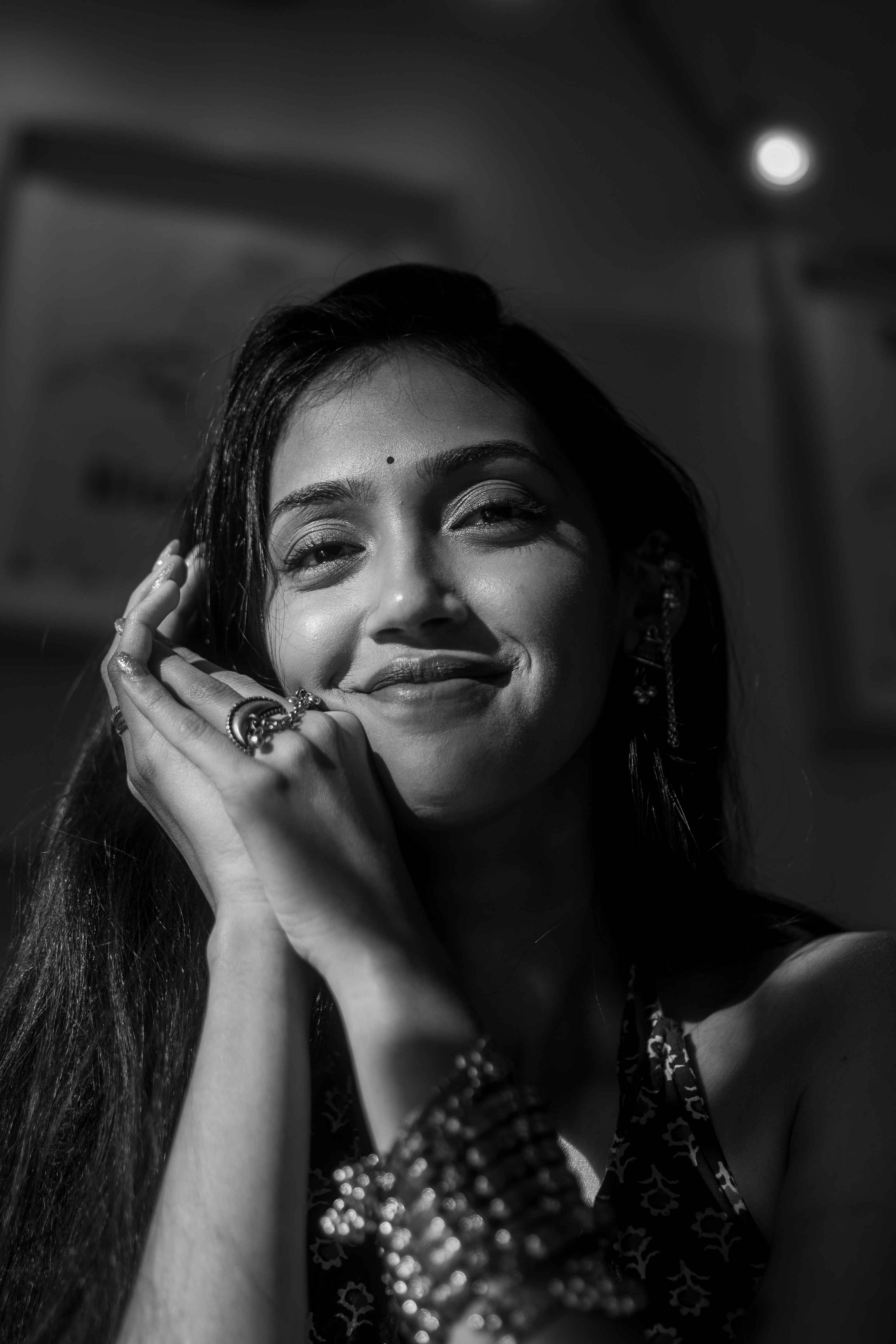 Black-and-white close portrait of a smiling woman resting her face on her hands.