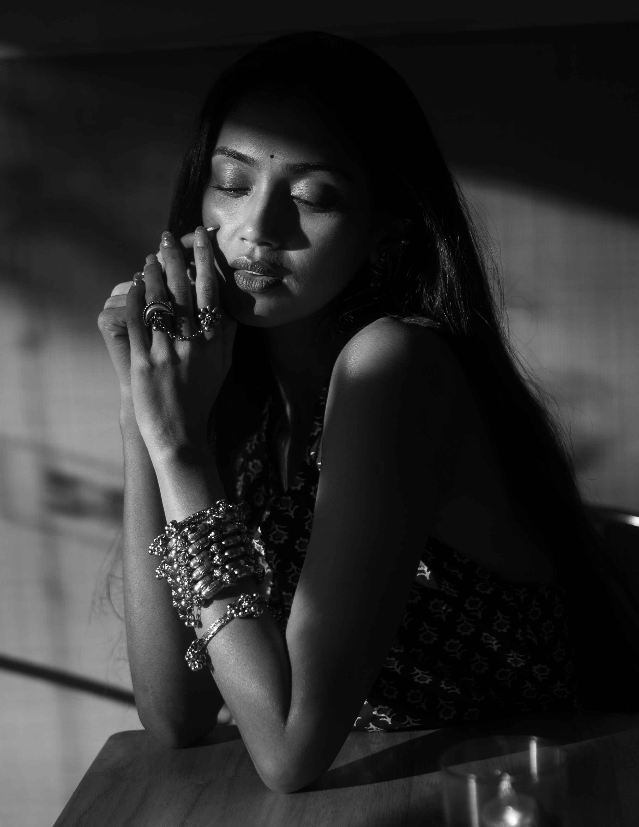 Black-and-white portrait of a woman resting her face on her hands.