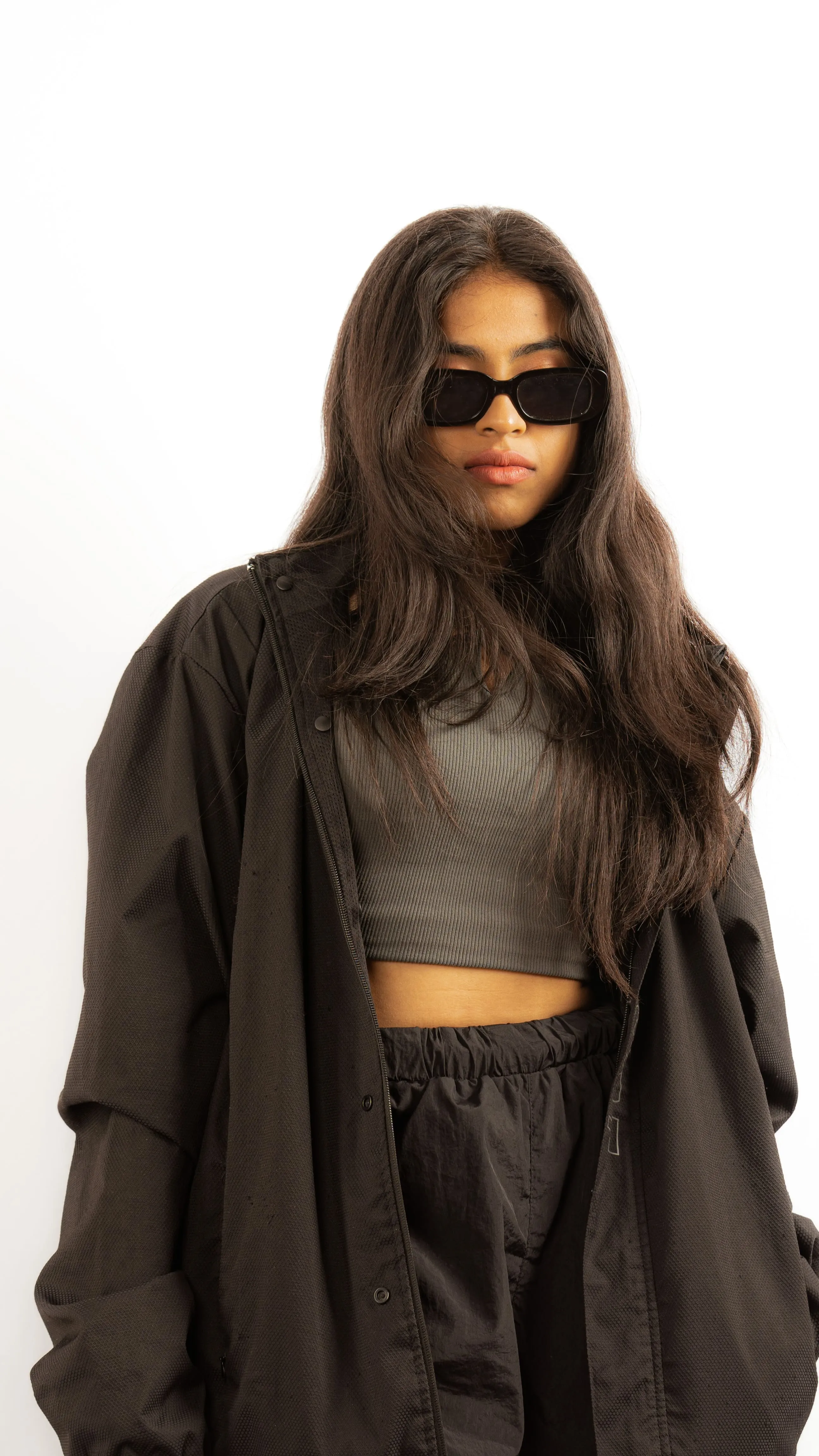 Woman in black sunglasses and a black jacket in a contemporary studio portrait.