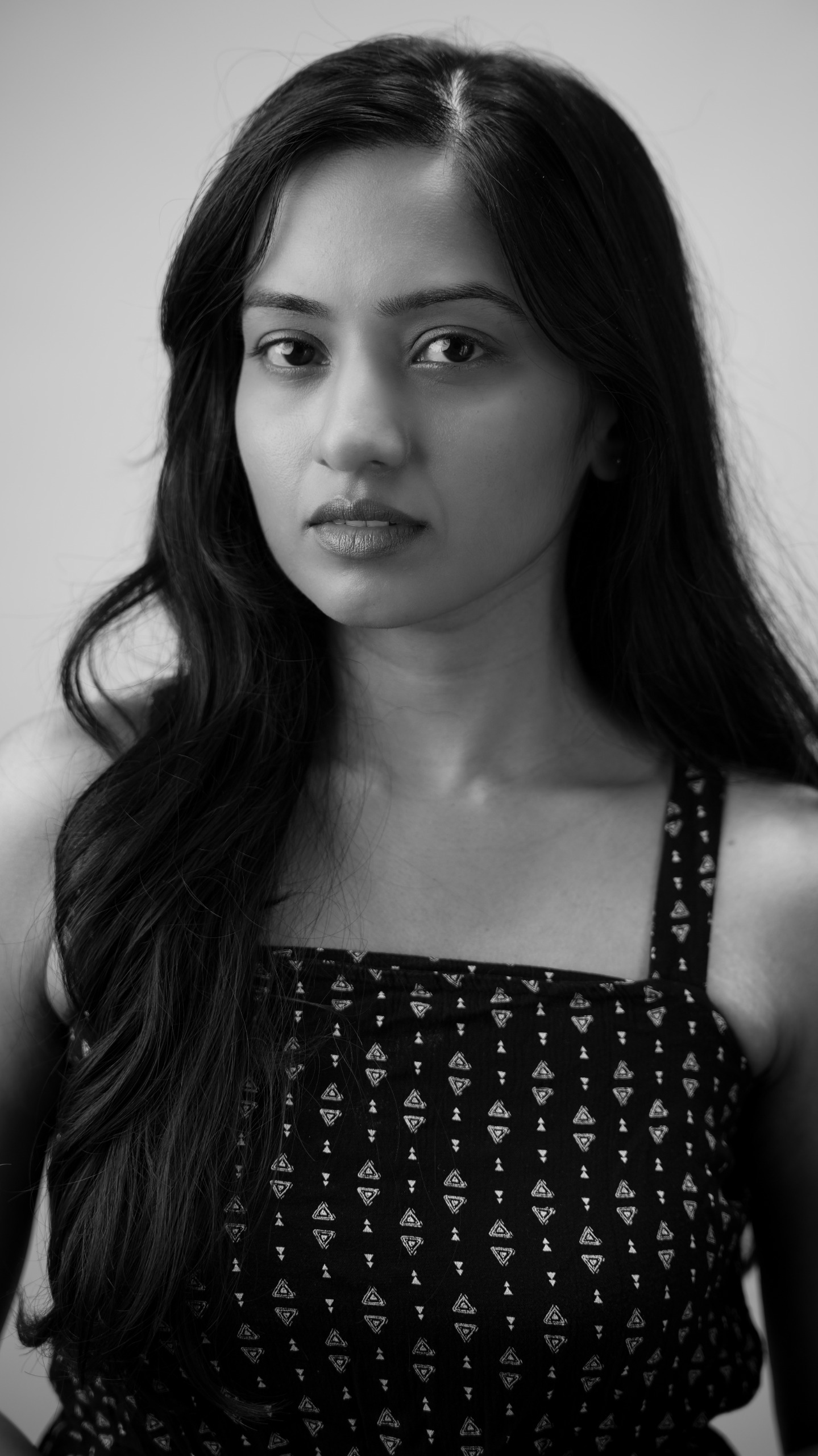 Black-and-white close portrait of a woman in a dark patterned sleeveless top.