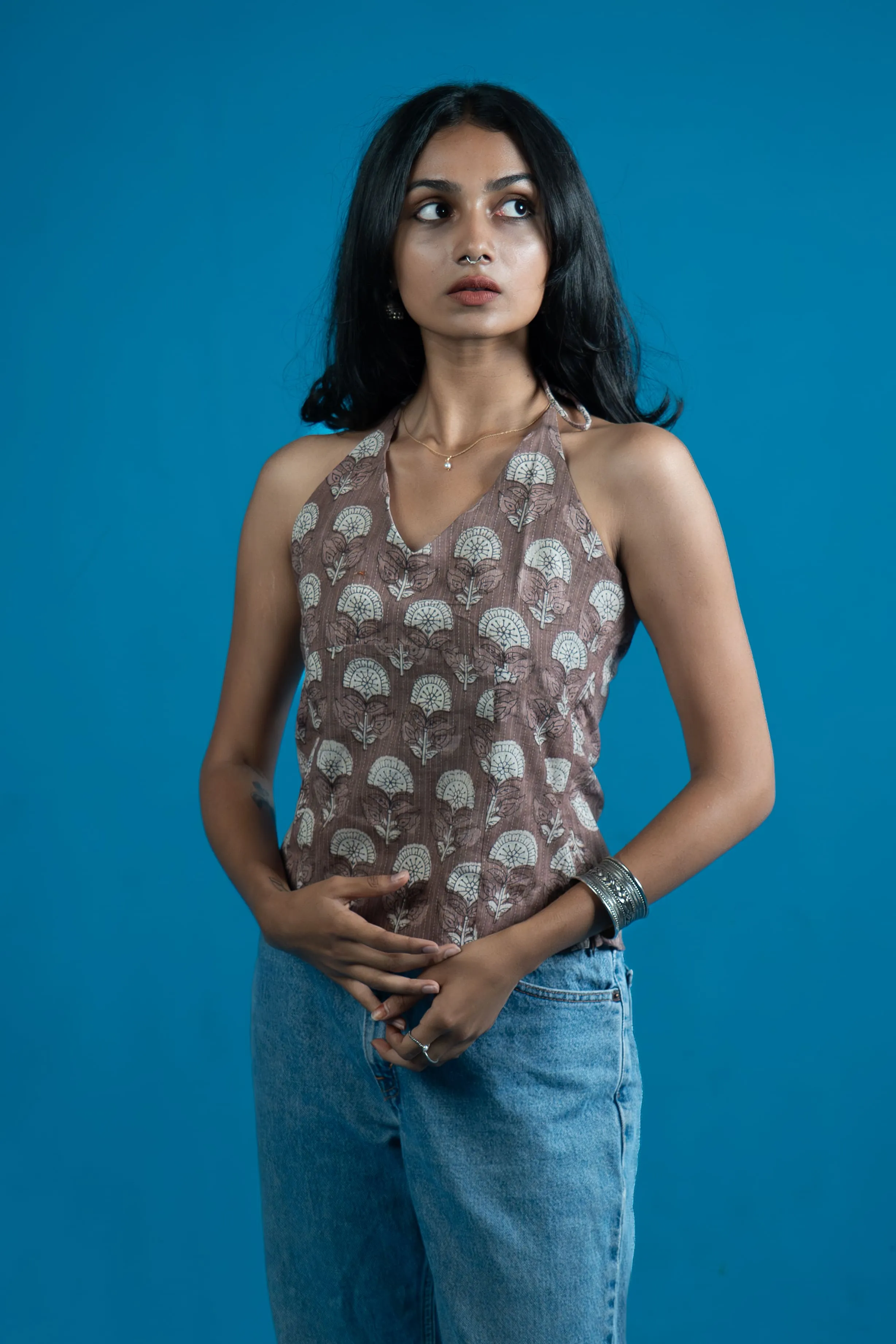 Woman in a brown floral halter-style top and jeans for Indyvarna's collection photography.