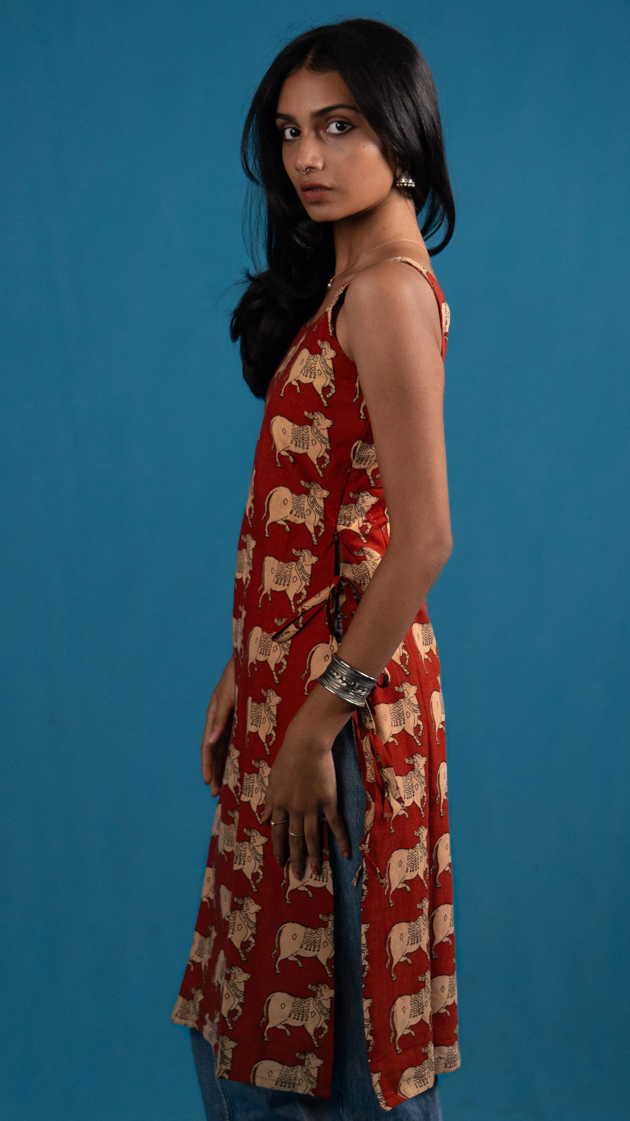 Side view of a red cow-print sleeveless top for Indyvarna.