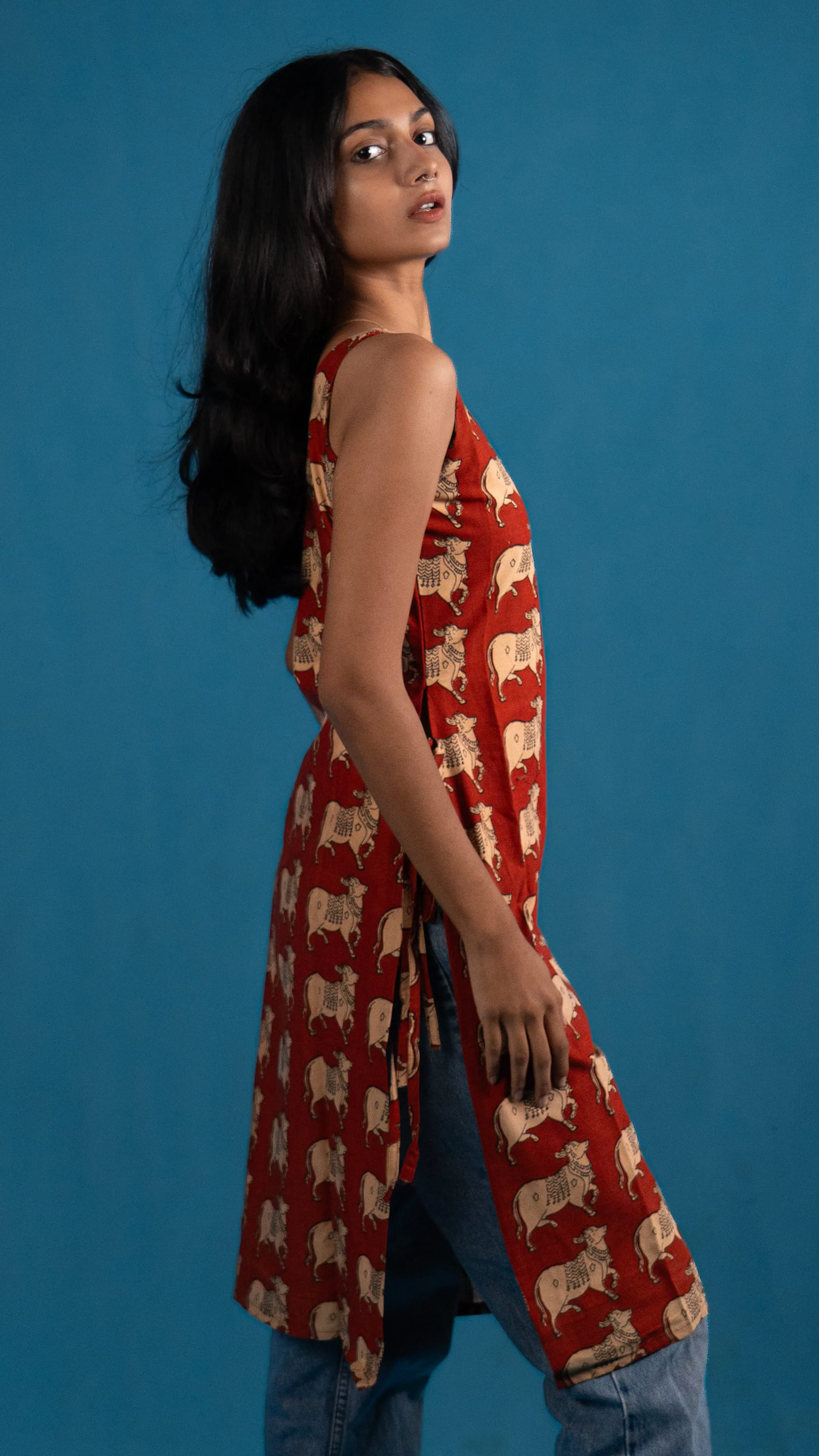 Side view of a red cow-print sleeveless top for Indyvarna.