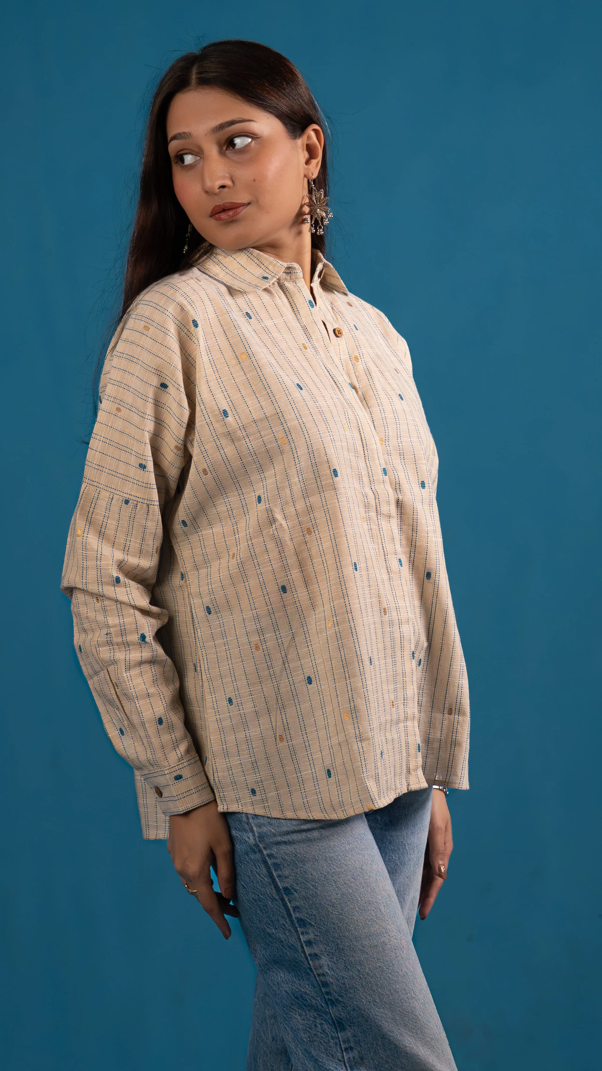Three-quarter portrait of a cream striped button-up shirt for Indyvarna.