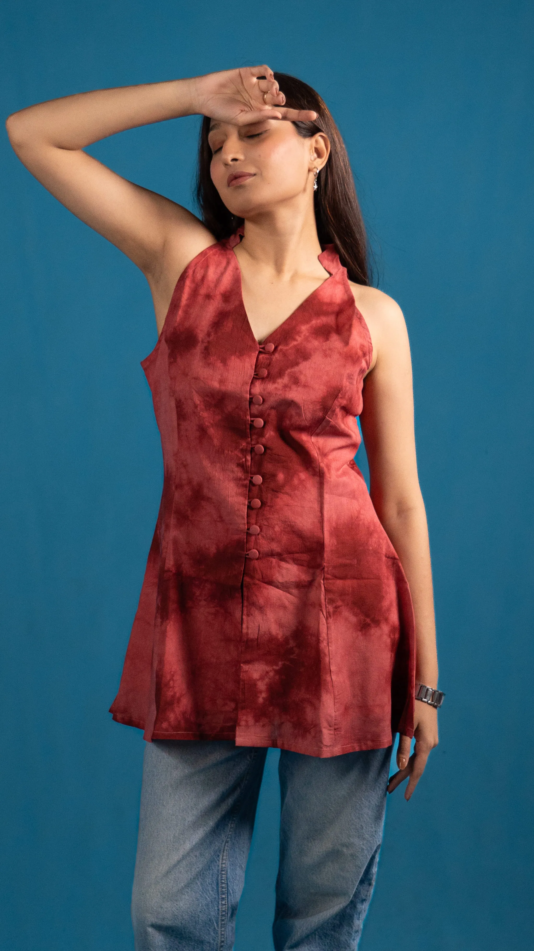 Woman in a red tie-dye sleeveless top with one arm raised for Indyvarna.