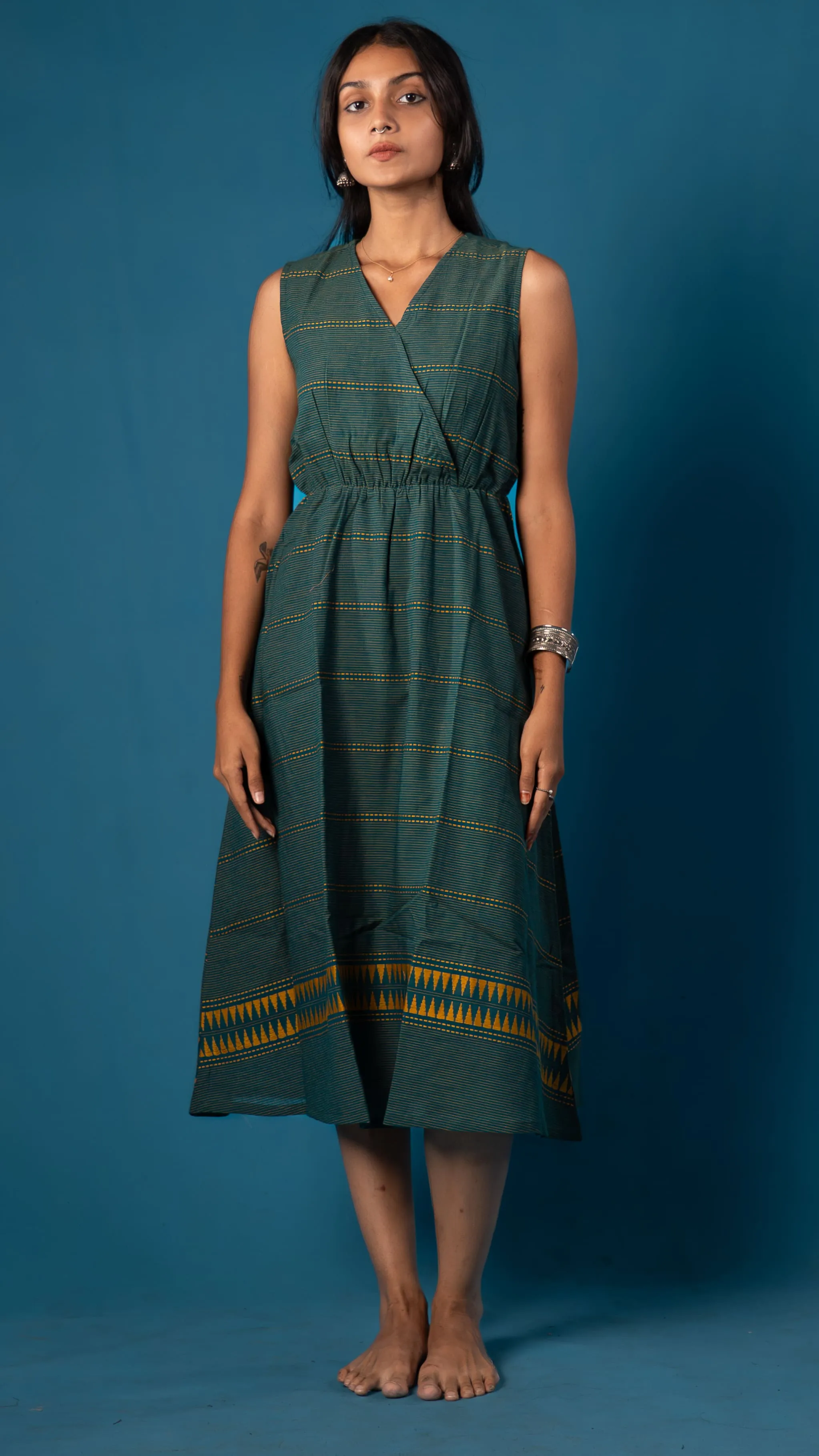 Woman in a green sleeveless dress with yellow striped details for Indyvarna.