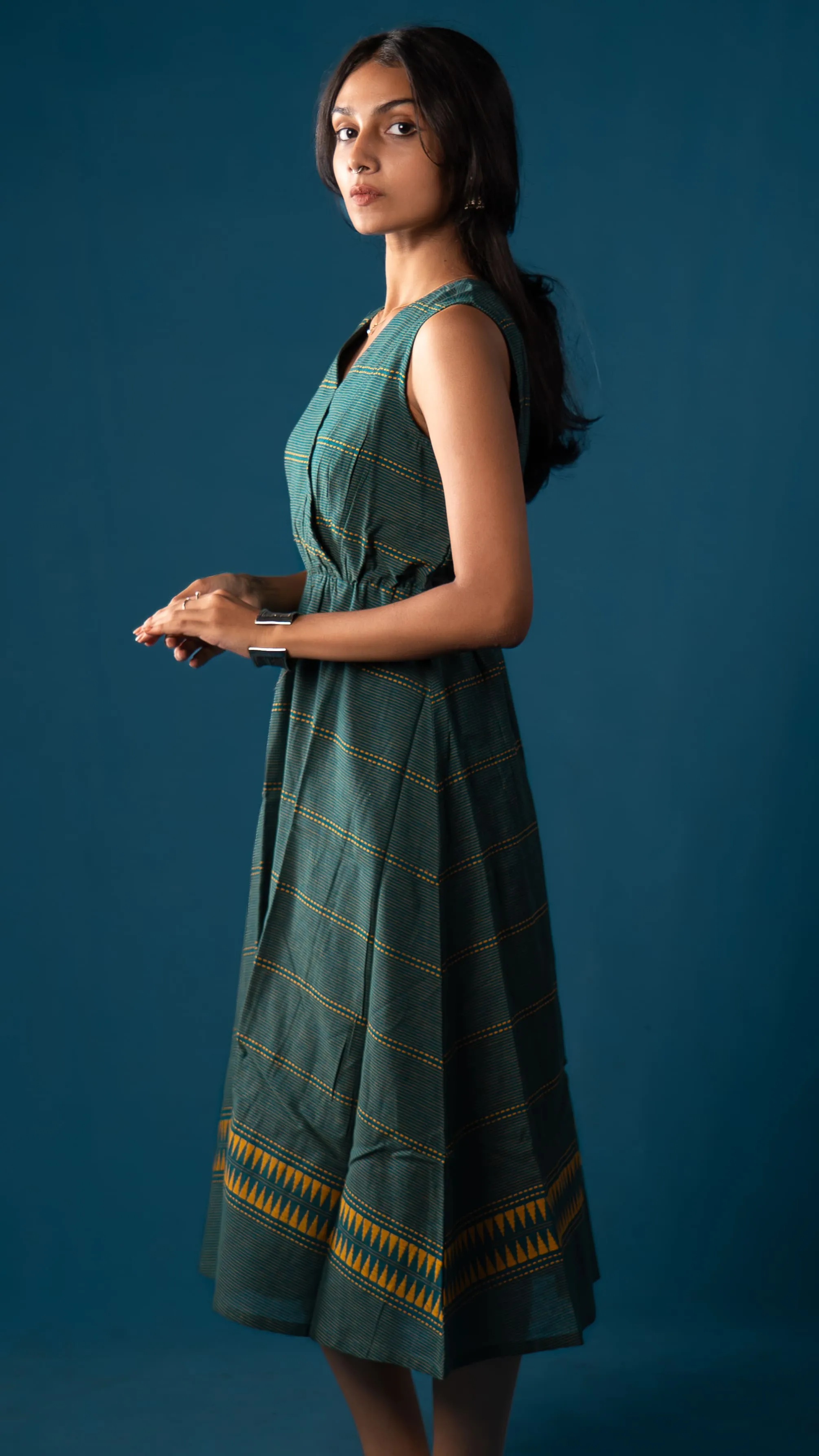 Side view of a green sleeveless dress with yellow striped details for Indyvarna.