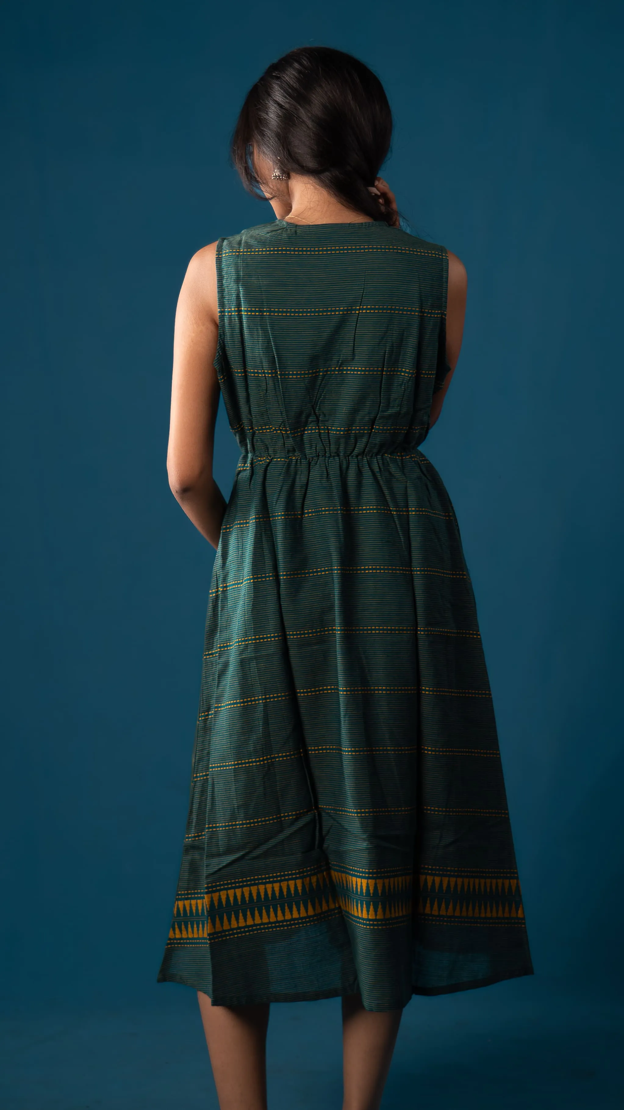 Back view of a green sleeveless dress with yellow striped details for Indyvarna.
