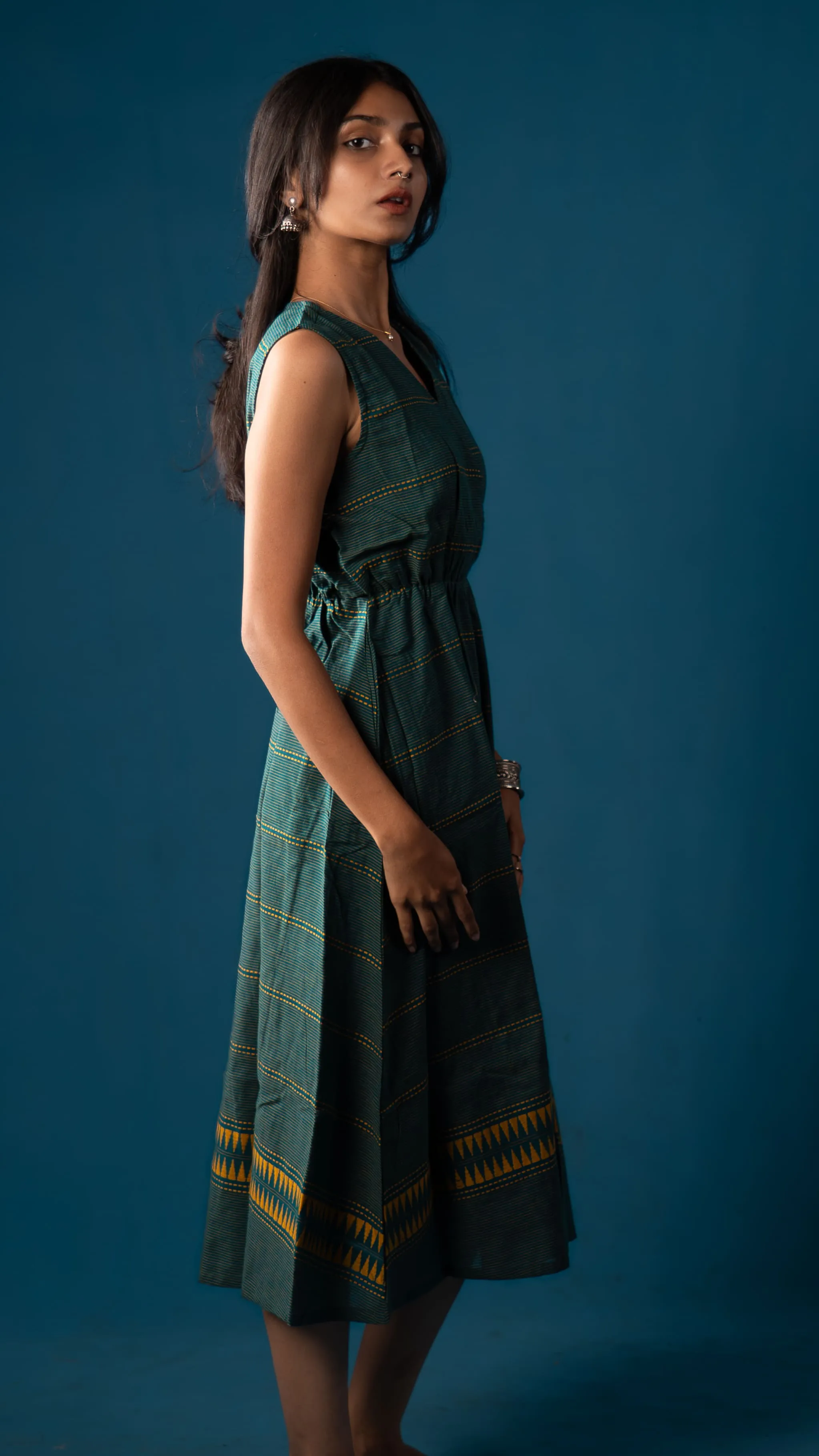 Side view of a green sleeveless dress with yellow striped details for Indyvarna.