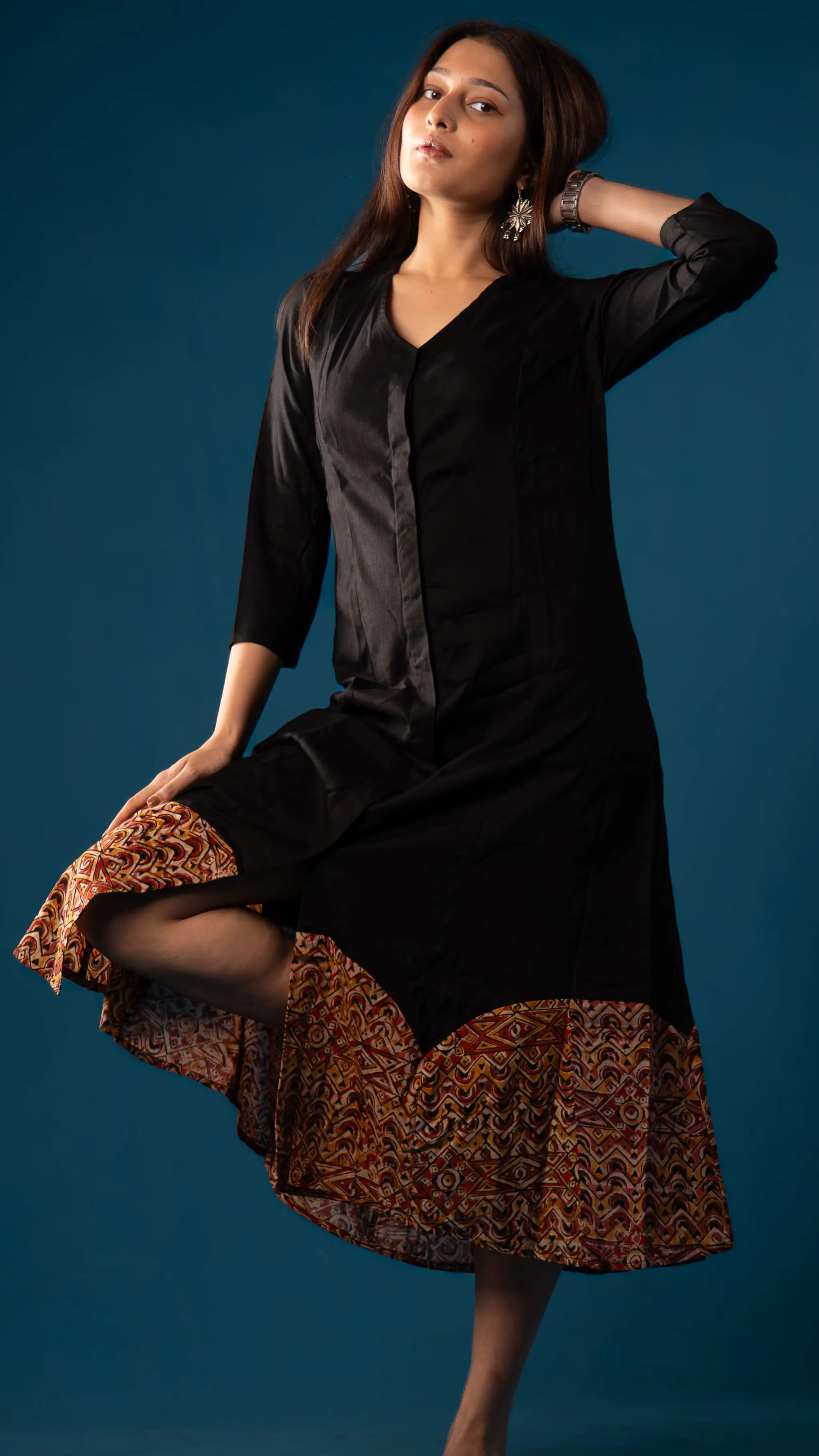 Woman in a black dress with a multicoloured geometric hem for Indyvarna.