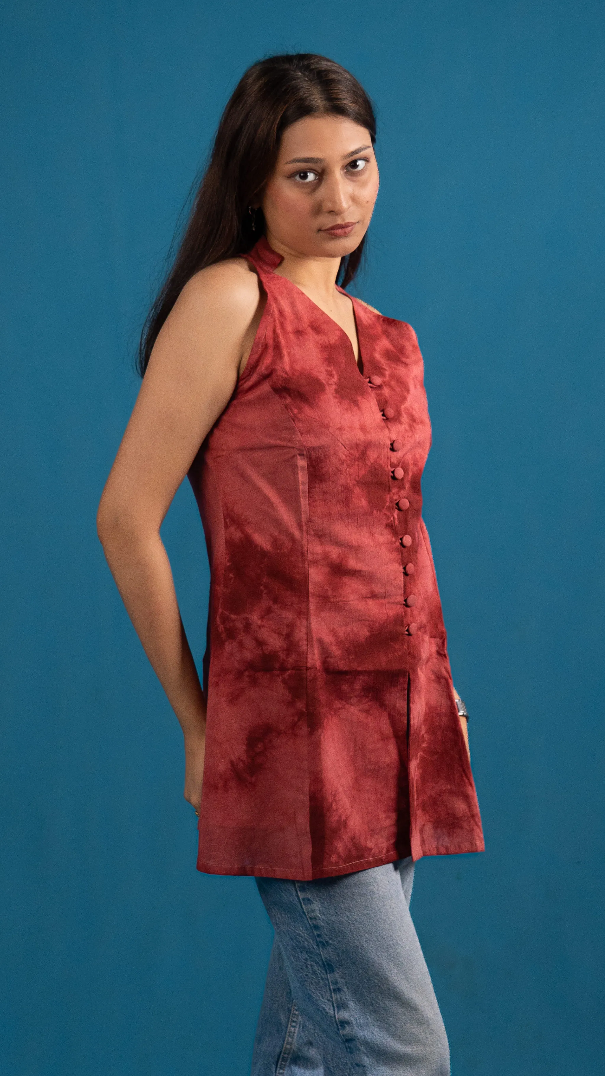 Woman in a red tie-dye sleeveless top posing against a blue backdrop for Indyvarna.