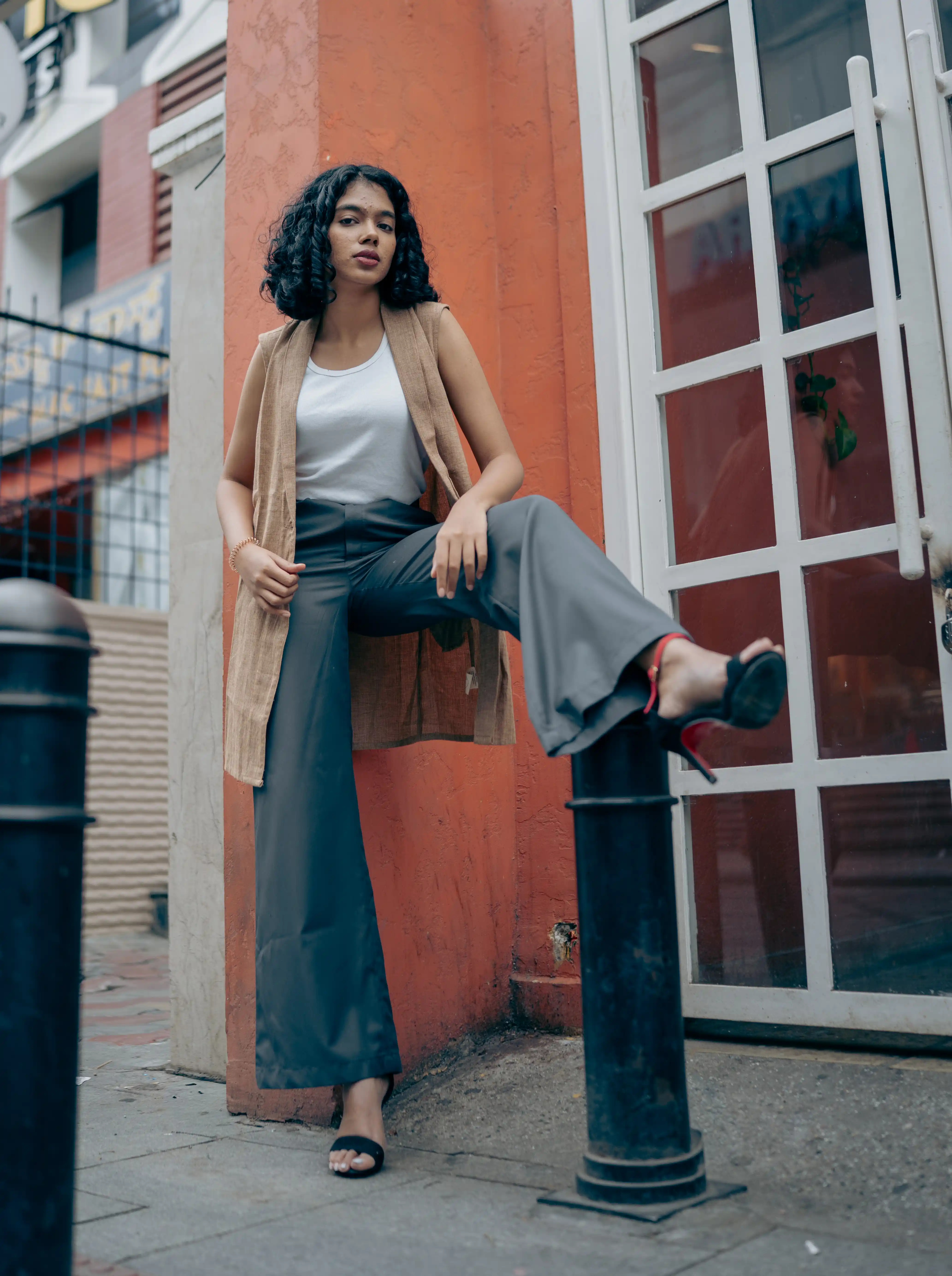Woman in a long tan sleeveless vest and dark trousers for Indyvarna.