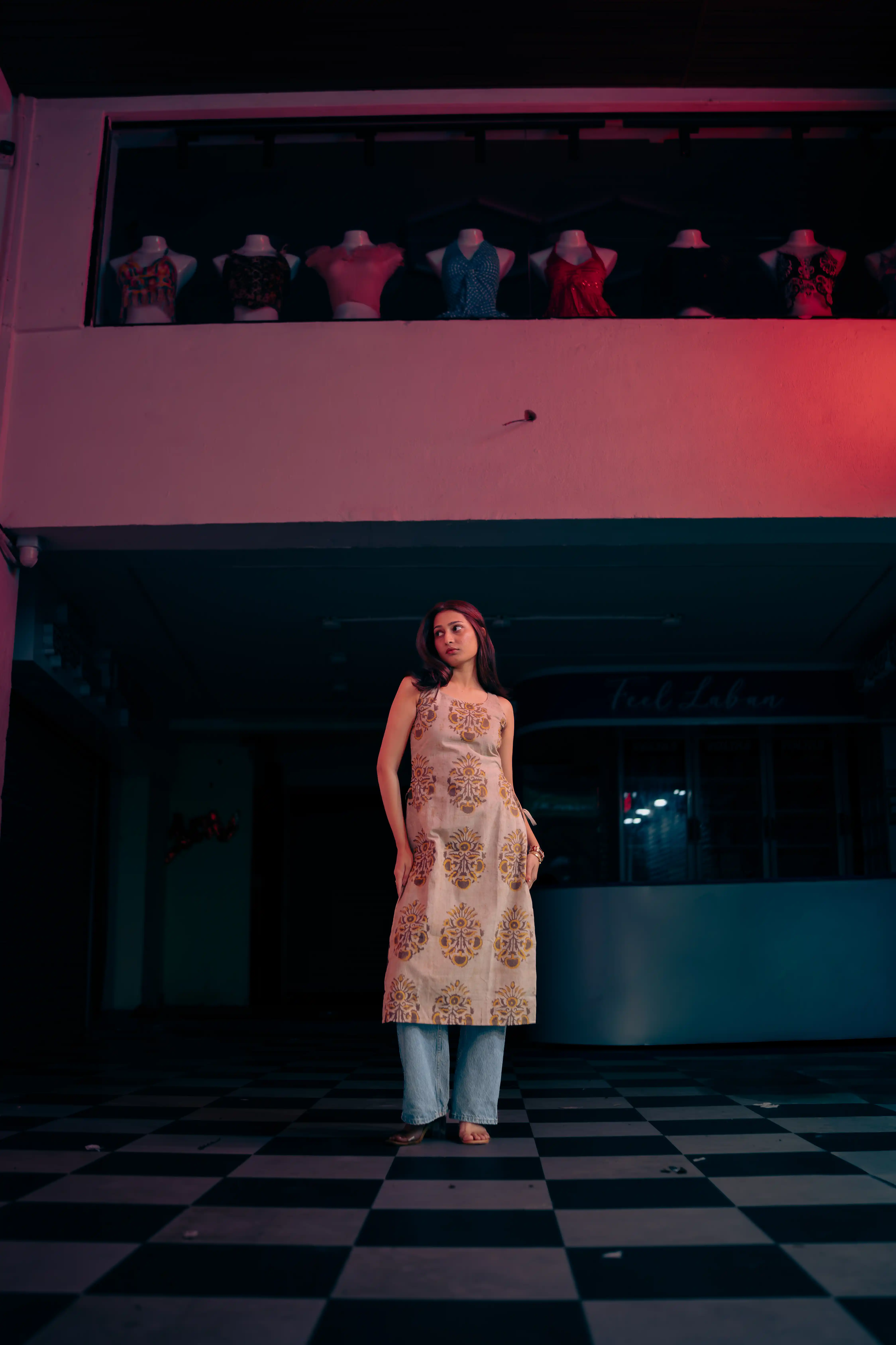 Woman in a cream floral sleeveless tunic and light blue jeans for Indyvarna.