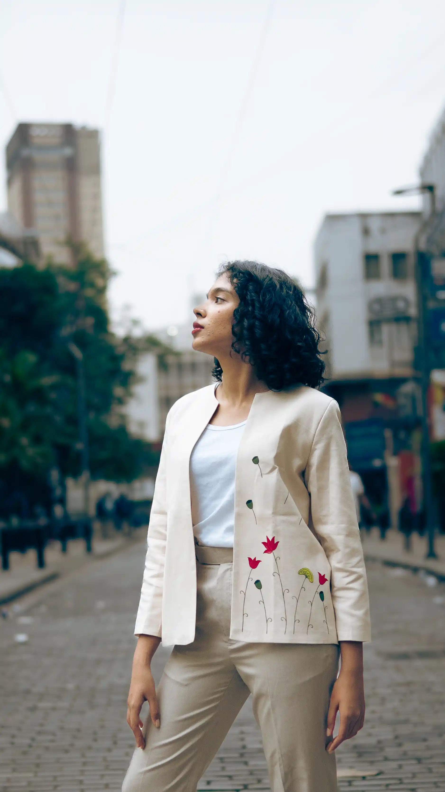 Woman in a white embroidered jacket and beige trousers for Indyvarna.