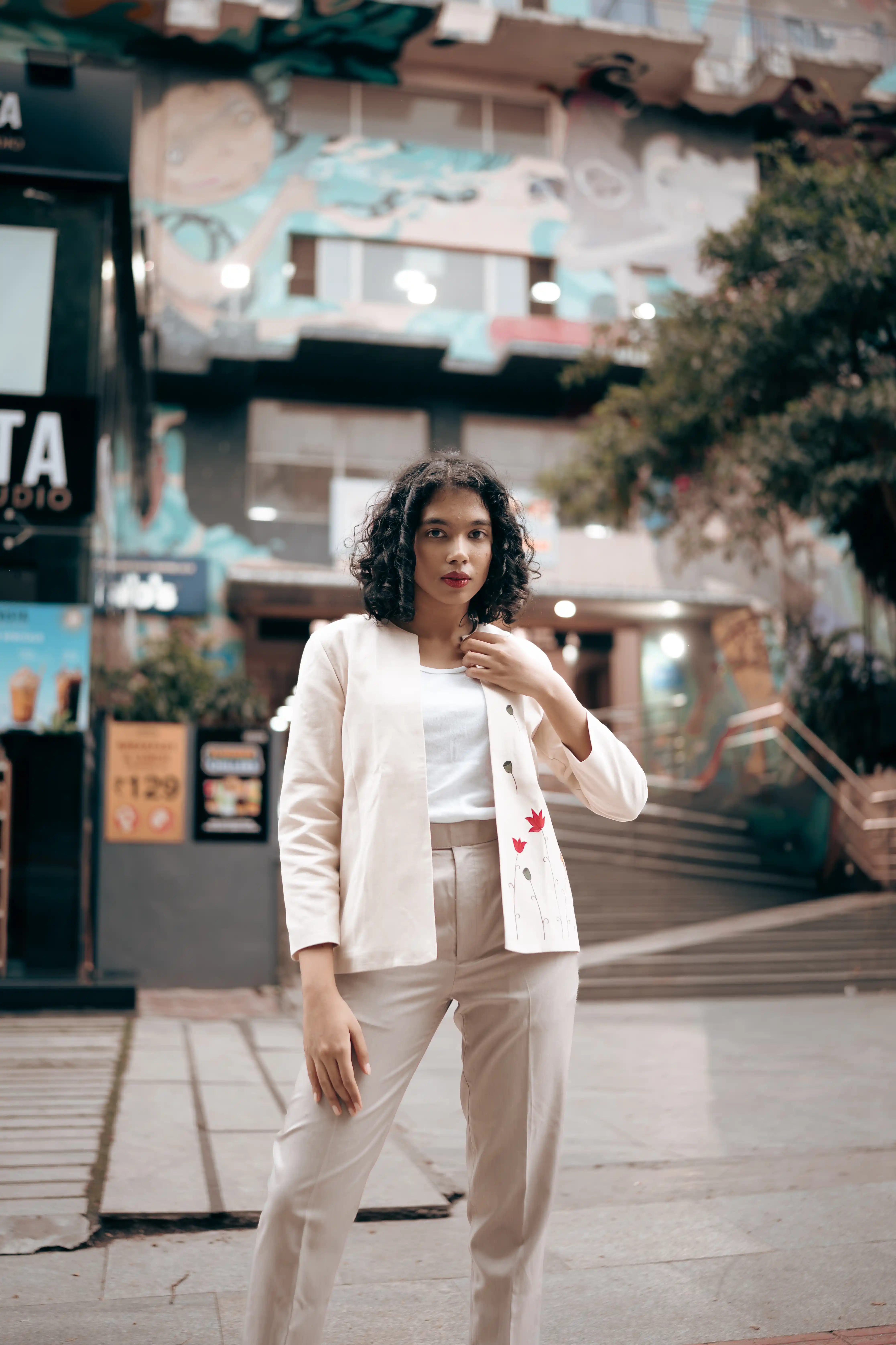 Woman in a white embroidered jacket and beige trousers for Indyvarna.