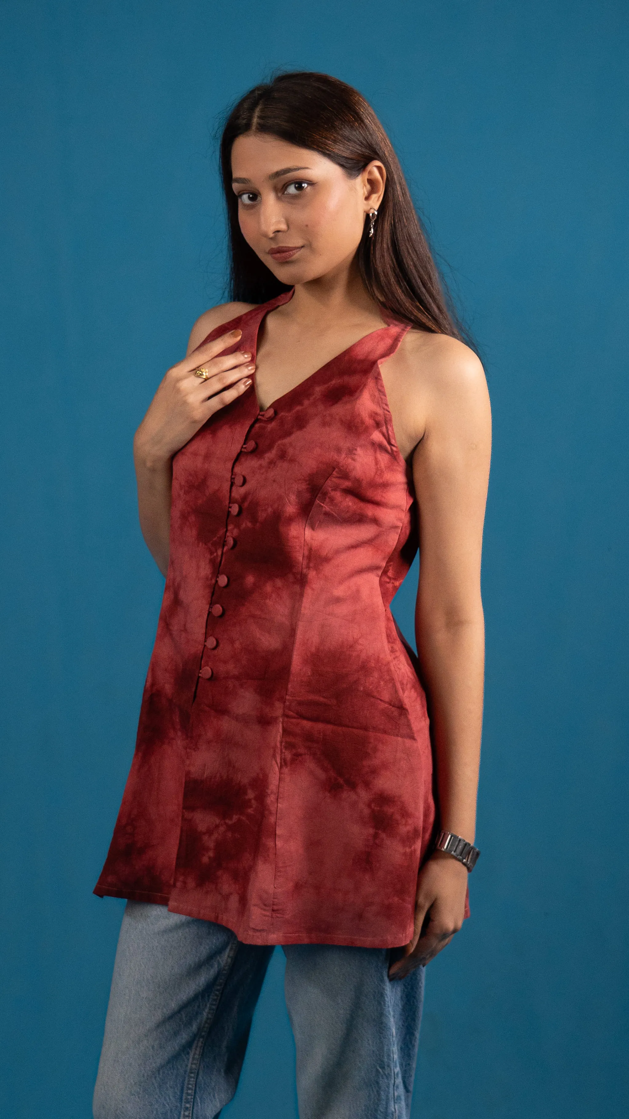 Side view of a woman in a red tie-dye sleeveless top for Indyvarna.