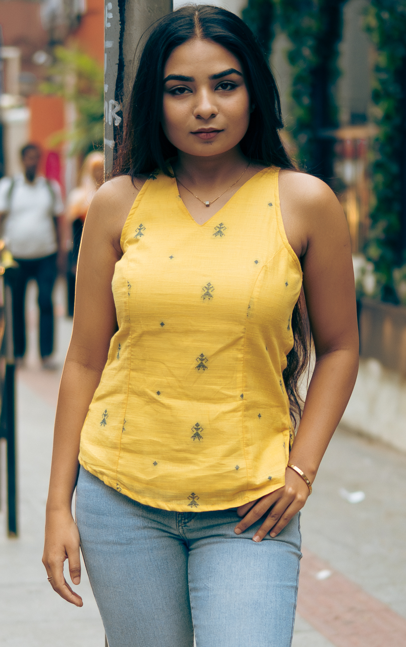 Woman in a yellow sleeveless top with dark motifs for Indyvarna.