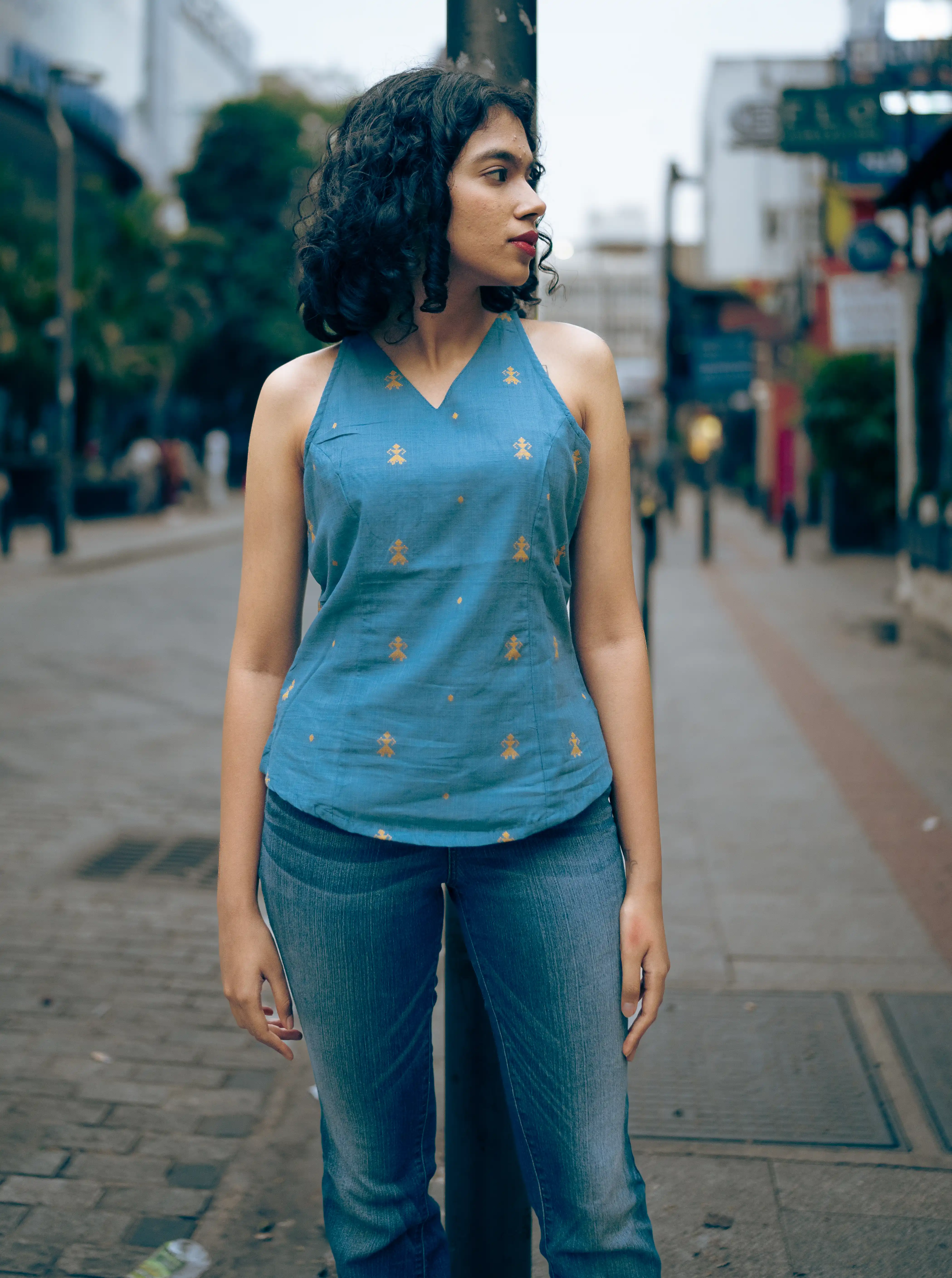 Woman in a blue sleeveless top with yellow motifs for Indyvarna.