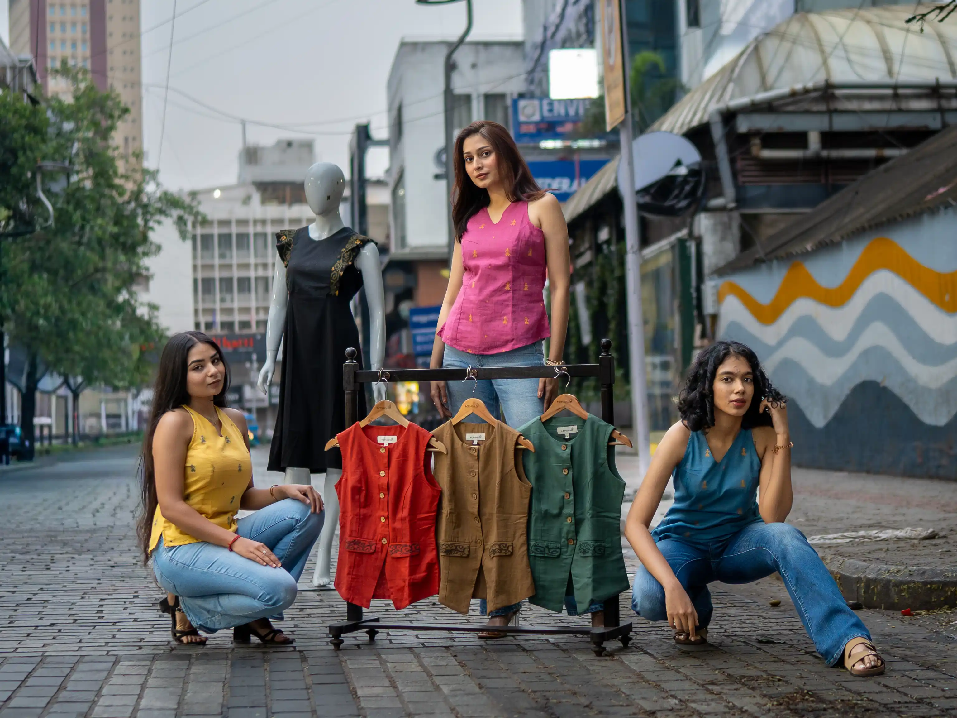 Three women with a rack of sleeveless vests for Indyvarna's collection photography.