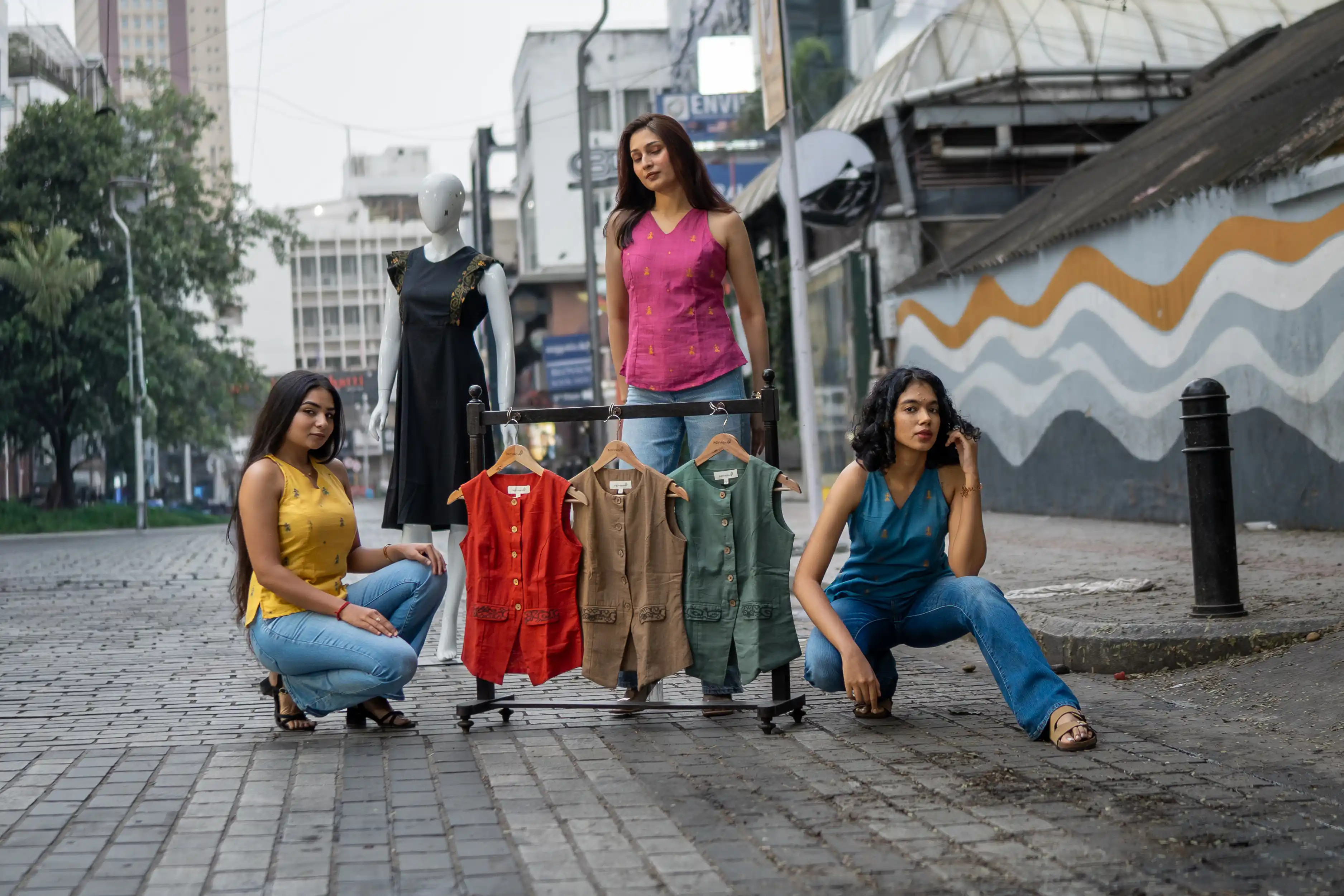Three women with a rack of sleeveless vests for Indyvarna's collection photography.