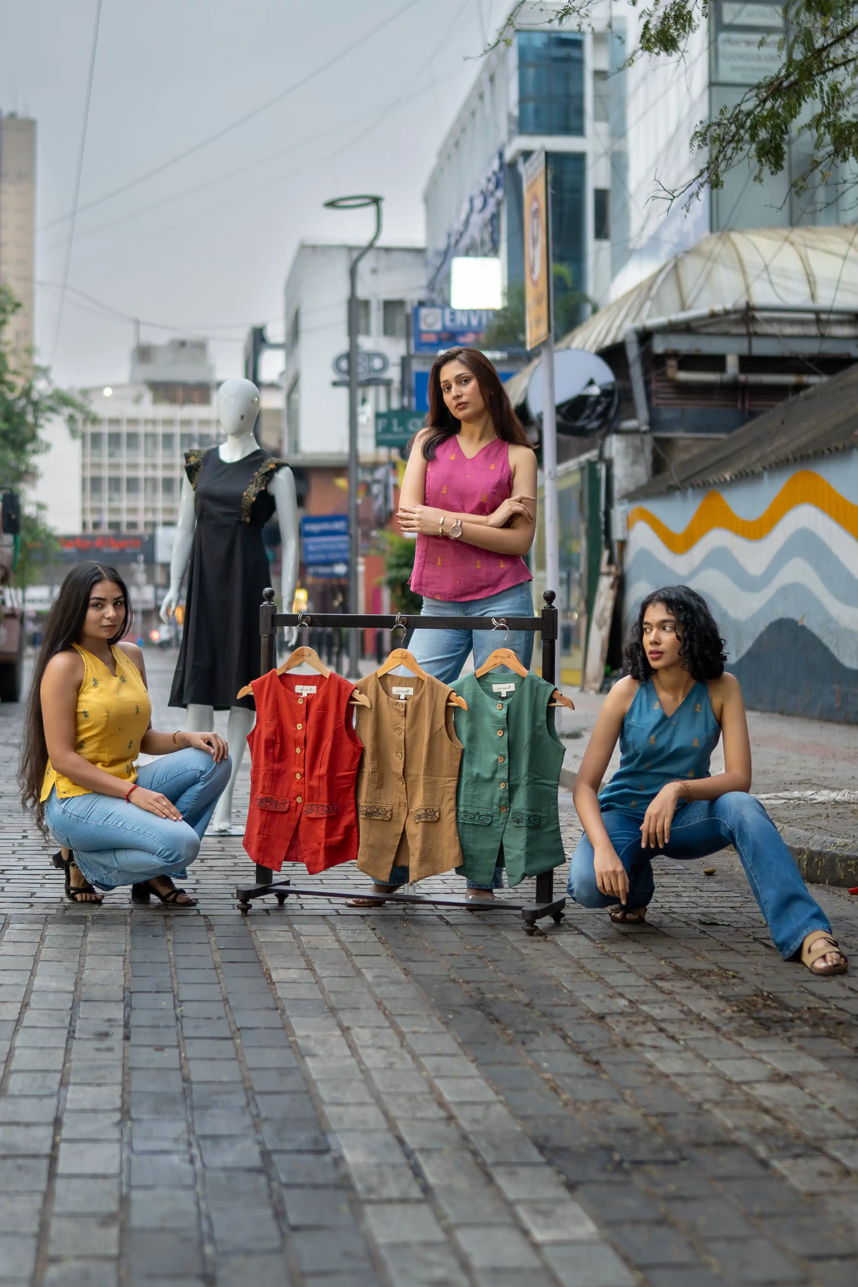 Three women with a rack of sleeveless vests for Indyvarna's collection photography.