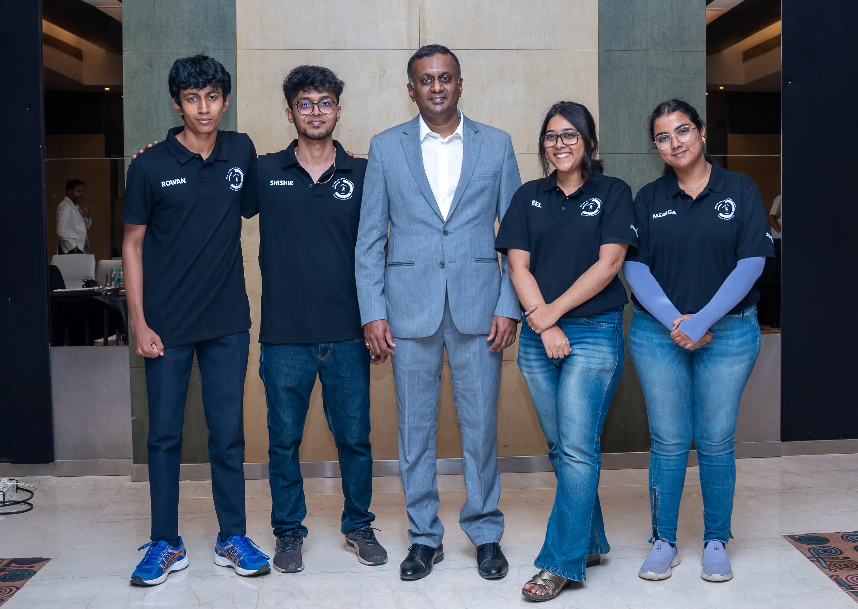 Five event participants pose in a hotel foyer for Skill Beyond Education.
