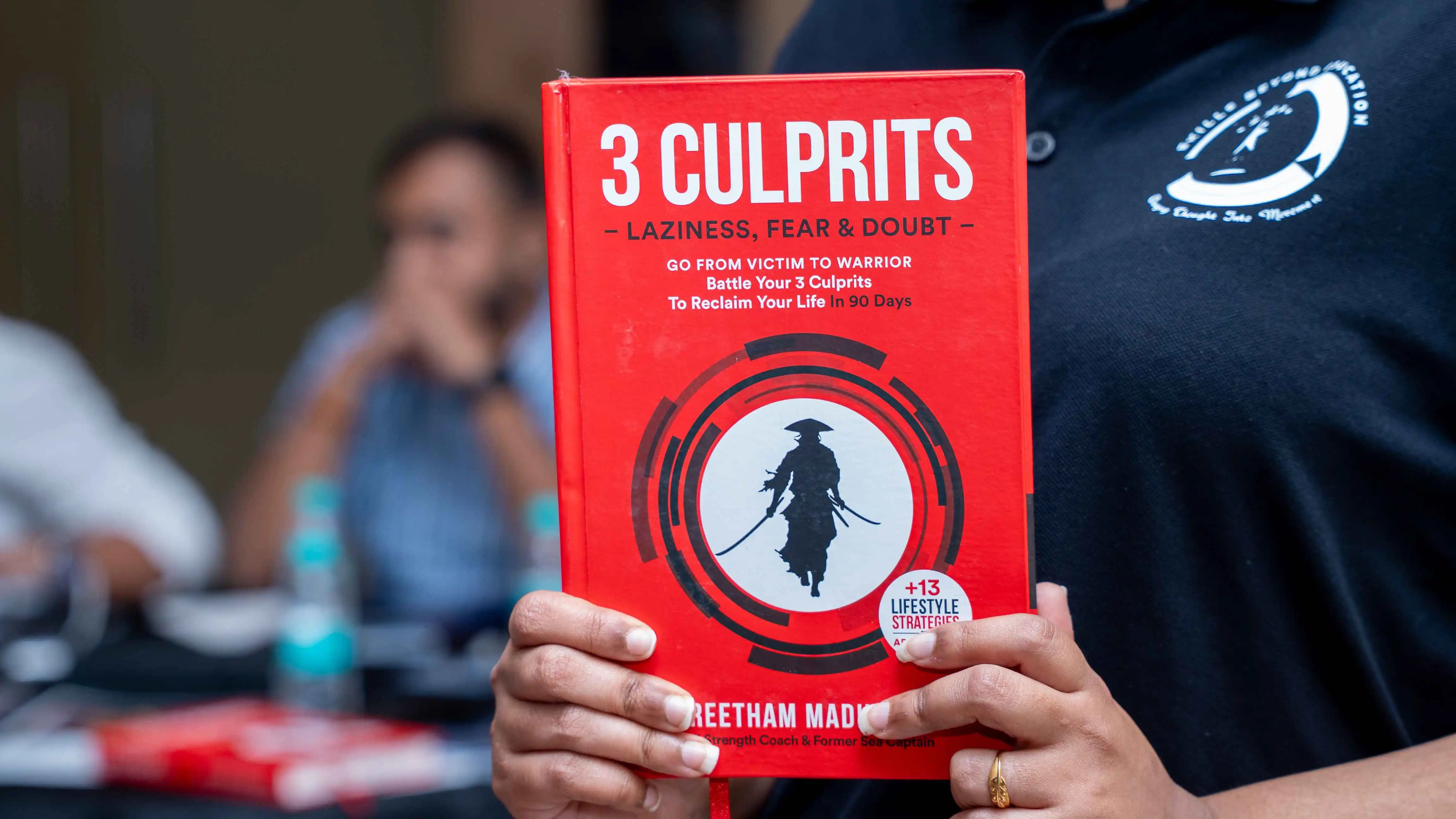 A participant holds the book 3 Culprits at a Skill Beyond Education event.