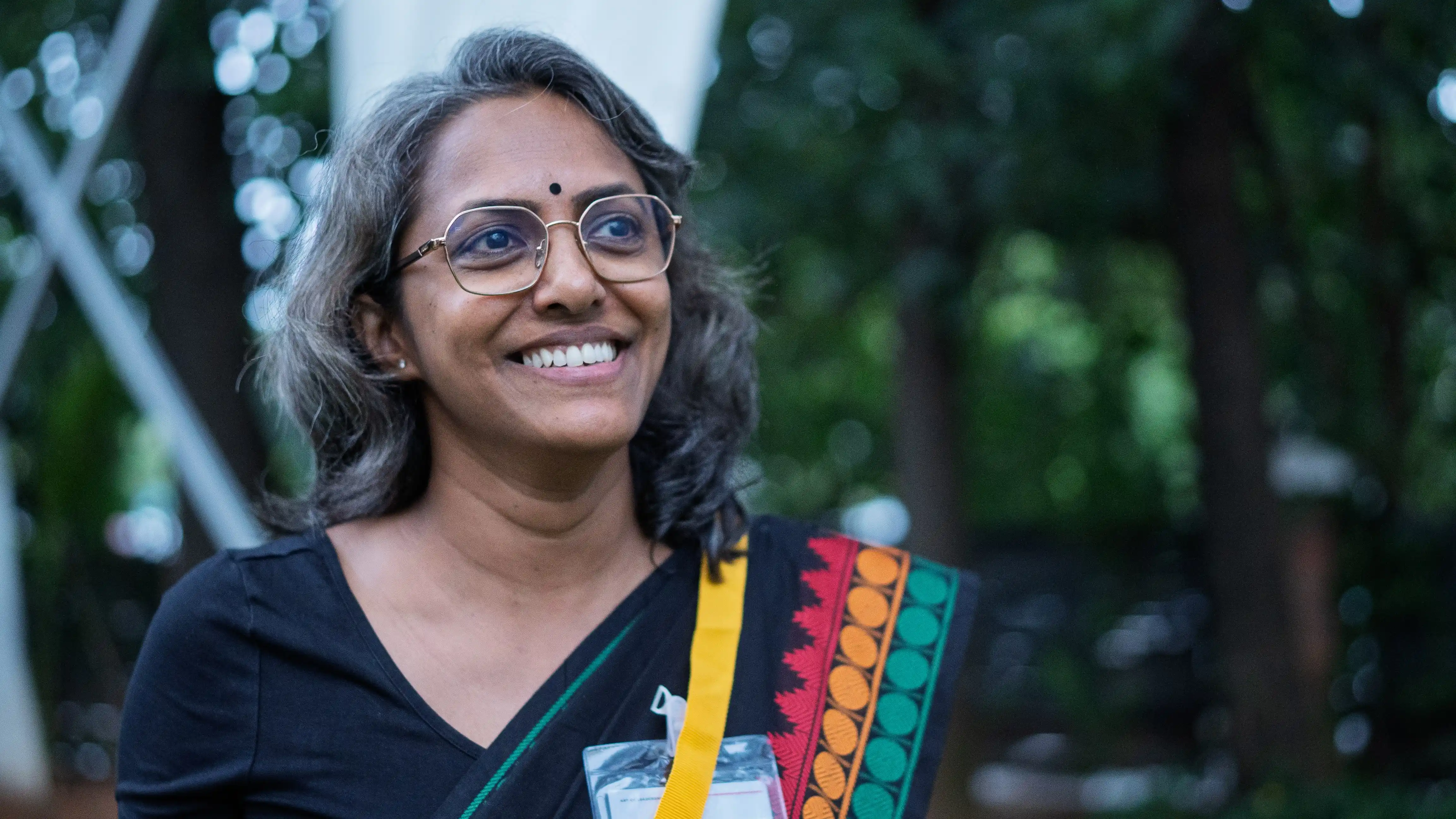 Smiling event attendee in a black sari for Skill Beyond Education.
