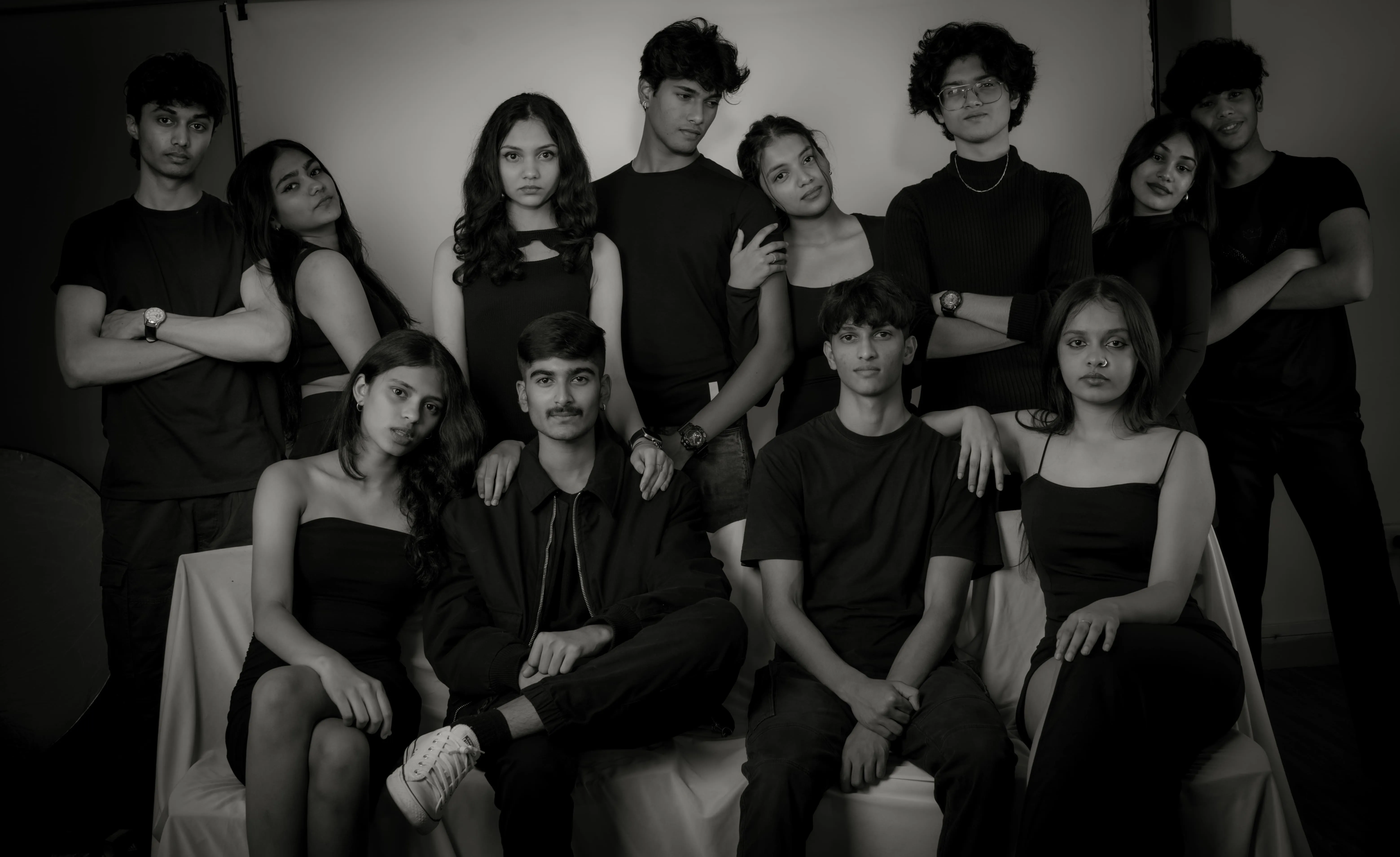 Twelve people in black pose in a two-row studio group portrait for a model team photography project.