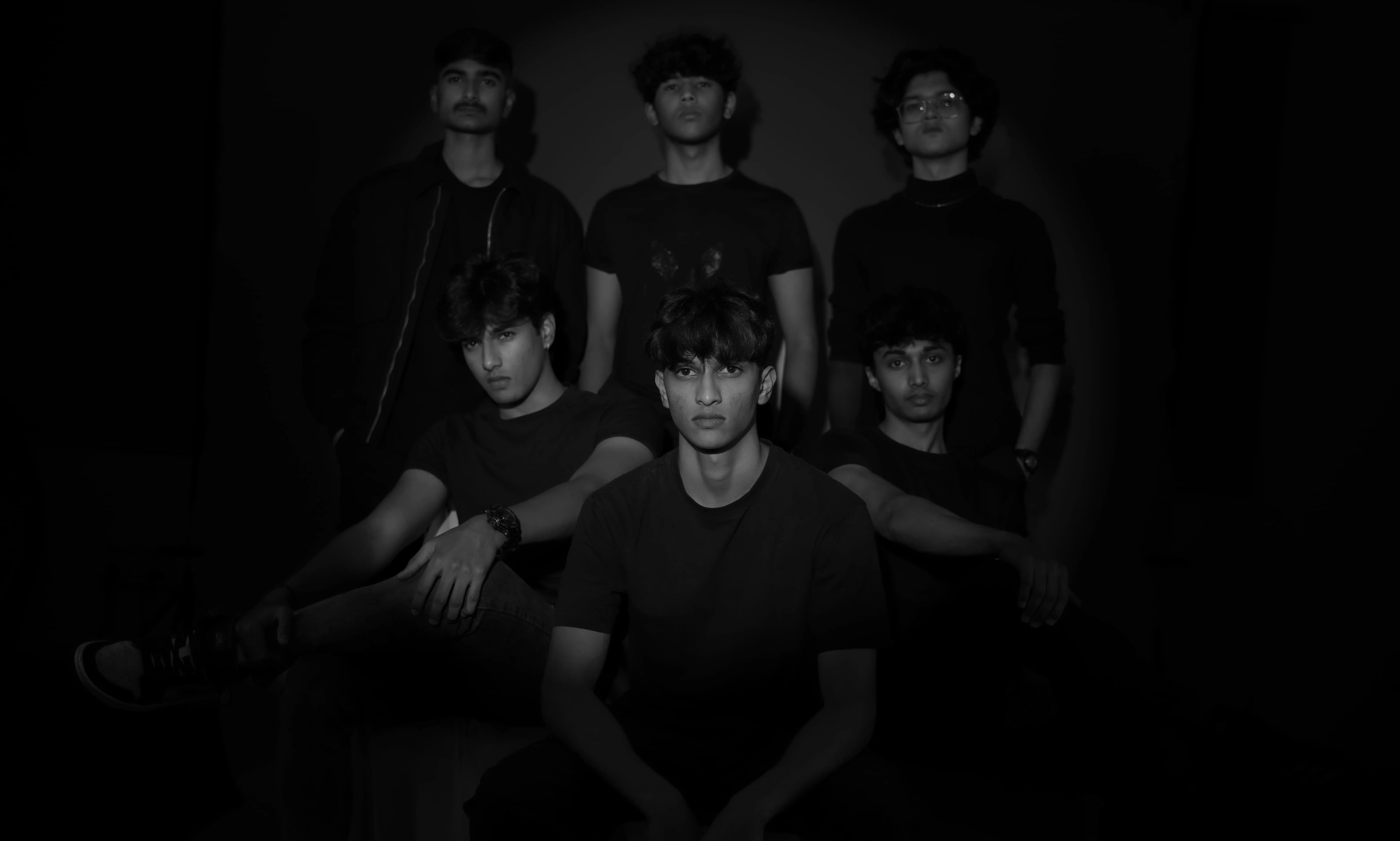 Six men in black pose in a two-row low-key studio portrait for a model team photography project.